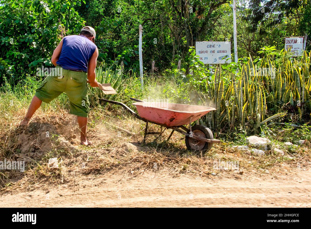 Un uomo che spezza lo sporco in una carriola . Lo stile di vita del vero popolo cubano. Foto Stock