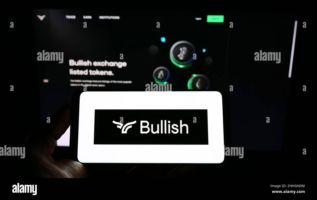 Persona che tiene il cellulare con il logo della società di scambio criptovaluta Bullish Global sullo schermo di fronte al sito web. Mettere a fuoco sul display del telefono. Foto Stock
