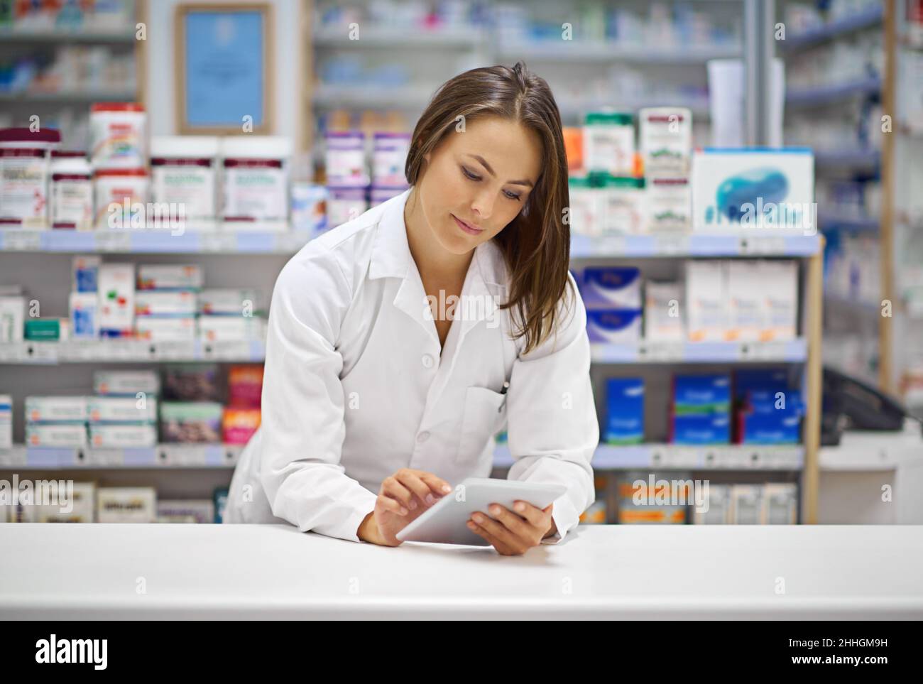 Monitoraggio digitale delle prescrizioni. Shot di un giovane farmacista attraente che lavora al banco di prescrizione. Foto Stock