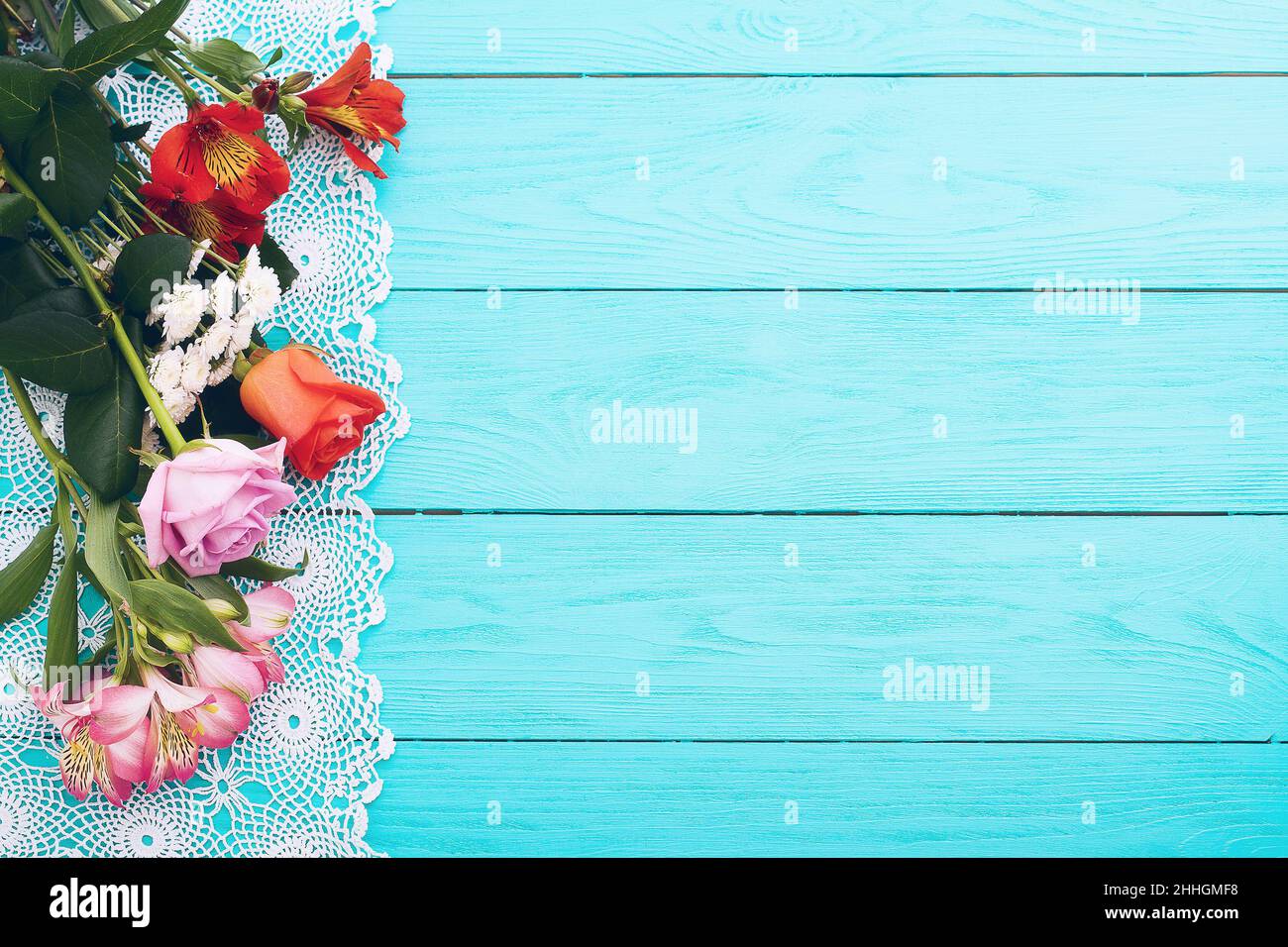 Carta di fiori e tovaglia di pizzo su sfondo di legno blu. Vista dall'alto e messa a fuoco selettiva. Foto Stock