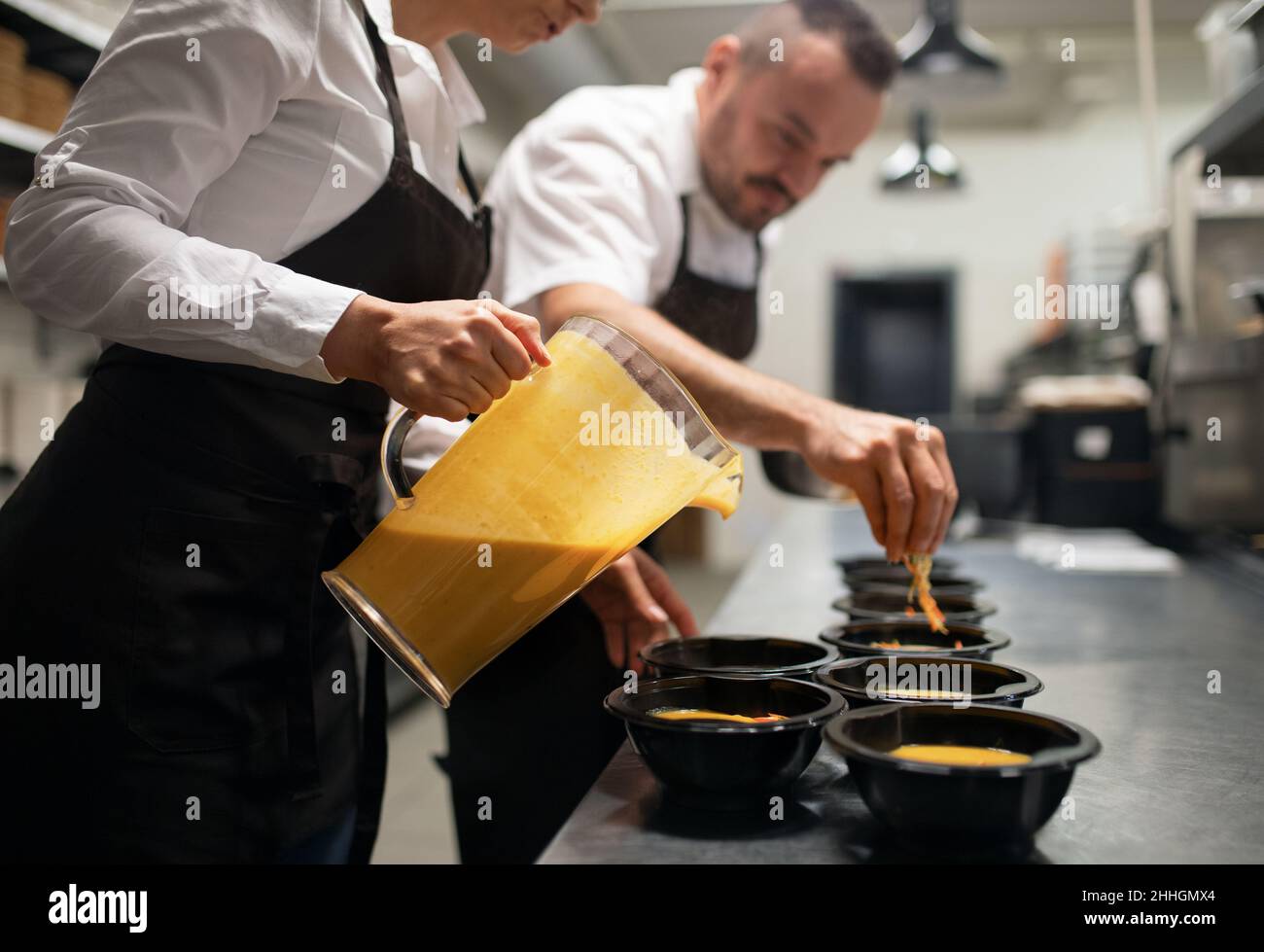 Chef e cuoco servono zuppa insieme all'interno nella cucina del ristorante. Foto Stock