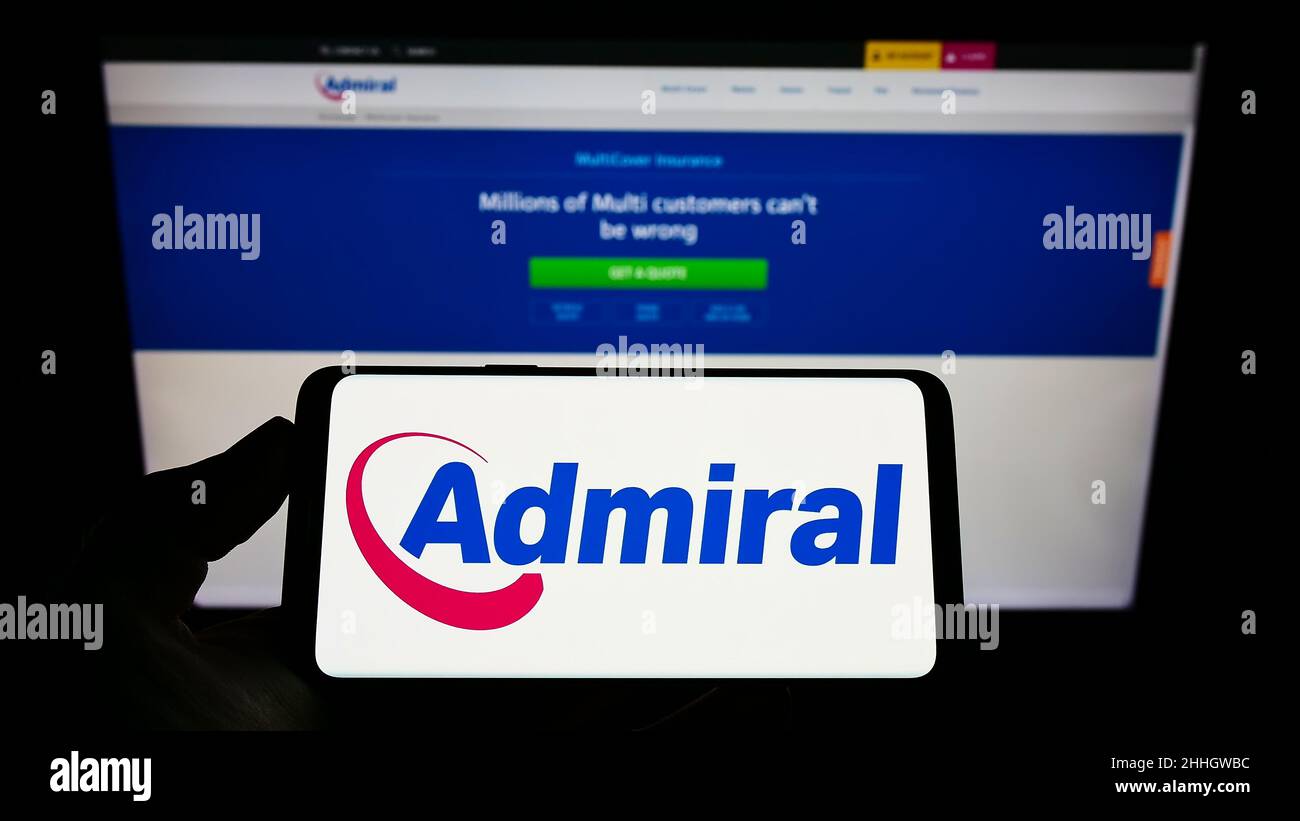 Persona che tiene uno smartphone con il logo della compagnia di assicurazioni britannica EUI Limited (Admiral) sullo schermo di fronte al sito web. Mettere a fuoco sul display del telefono. Foto Stock