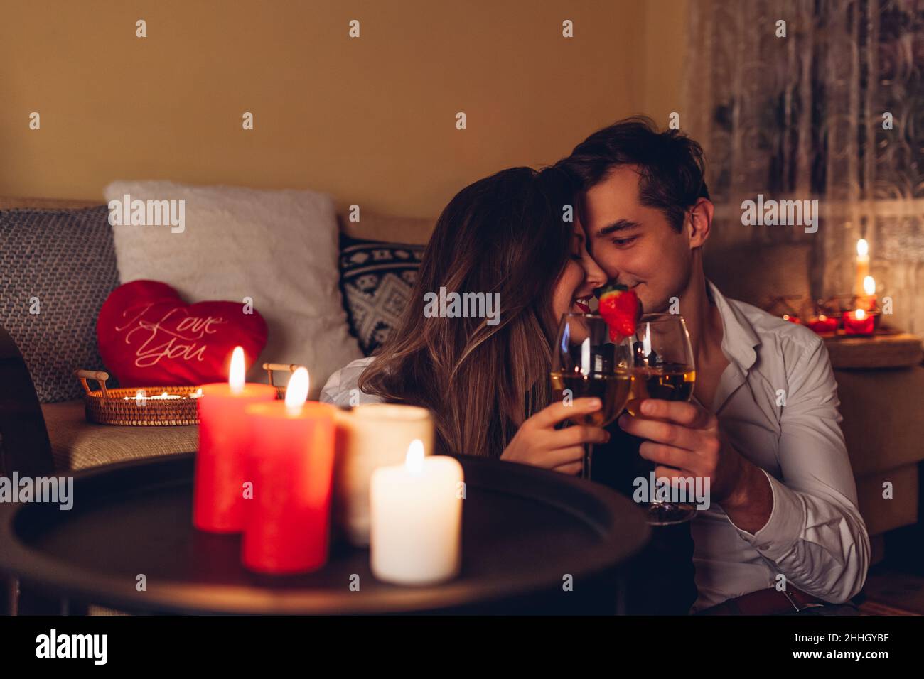 Giovane San Valentino coppia in amore calici che bevono vino con fragole cena romantica con candele festeggiavano a casa di notte Foto Stock