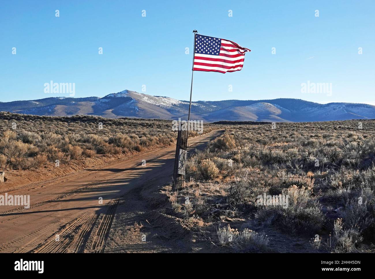 Una bandiera americana solana vola a un cancello ranch nella campagna dell'Oregon. Centinaia di nuove bandiere sono salite a porte simili nelle aziende agricole e nei ranch in tutto il centro Foto Stock