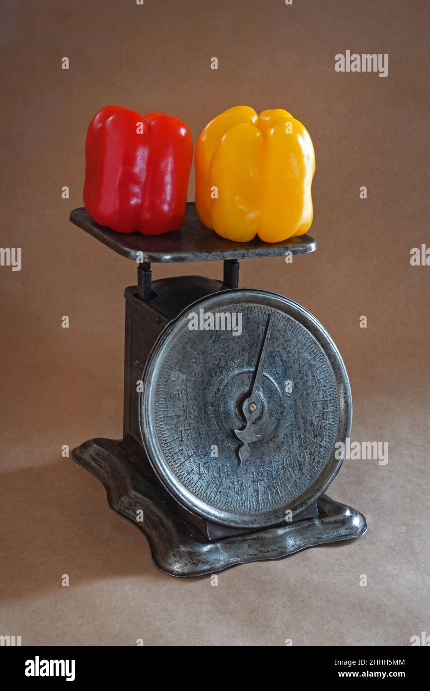 Ritratto di una bilancia da cucina d'epoca che pesa peperoni dai colori vivaci. Foto Stock