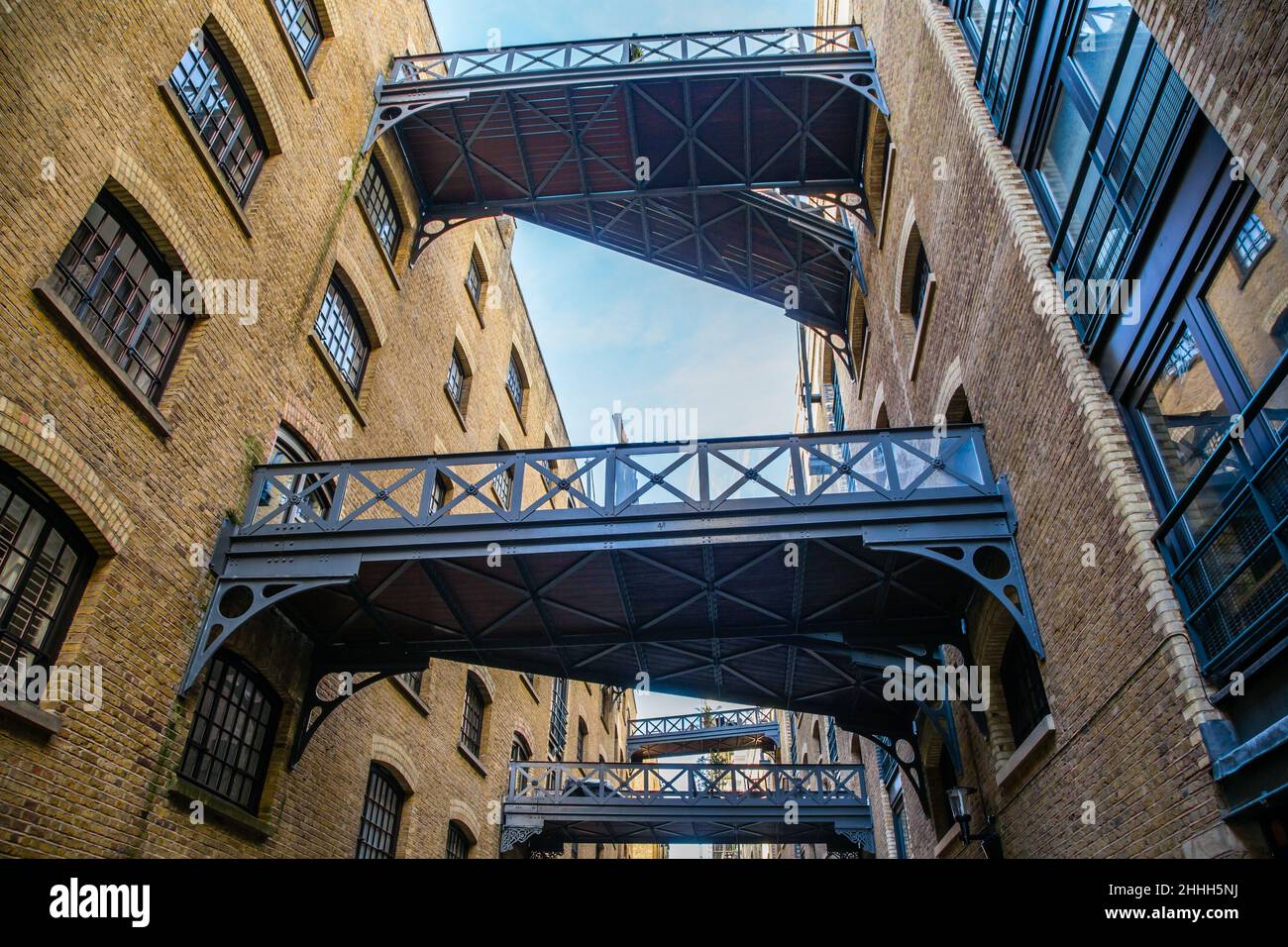 Shad Thames Road e ponti di banchina dietro i vecchi magazzini del fiume, Londra Foto Stock