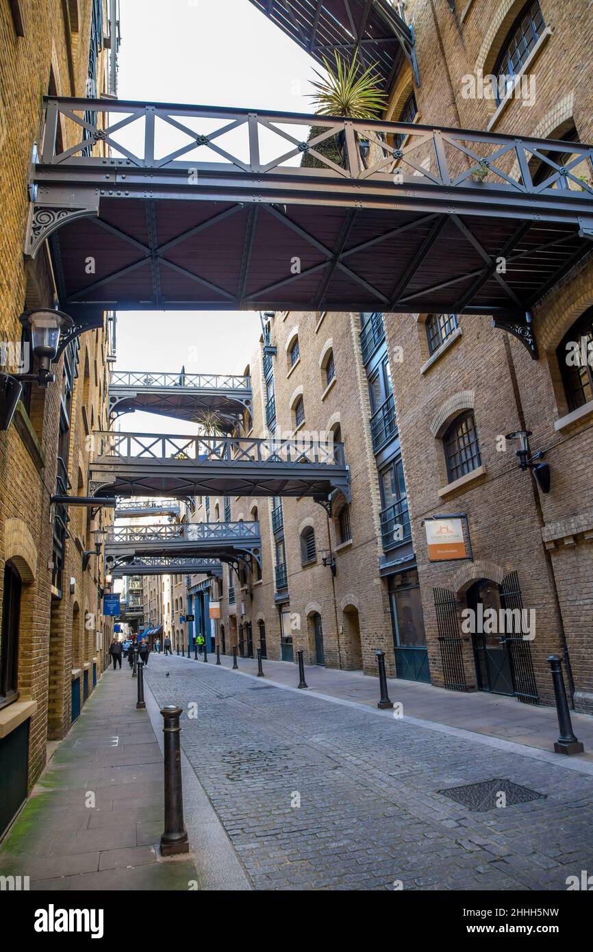 Shad Thames Road e ponti di banchina dietro i vecchi magazzini del fiume, Londra Foto Stock