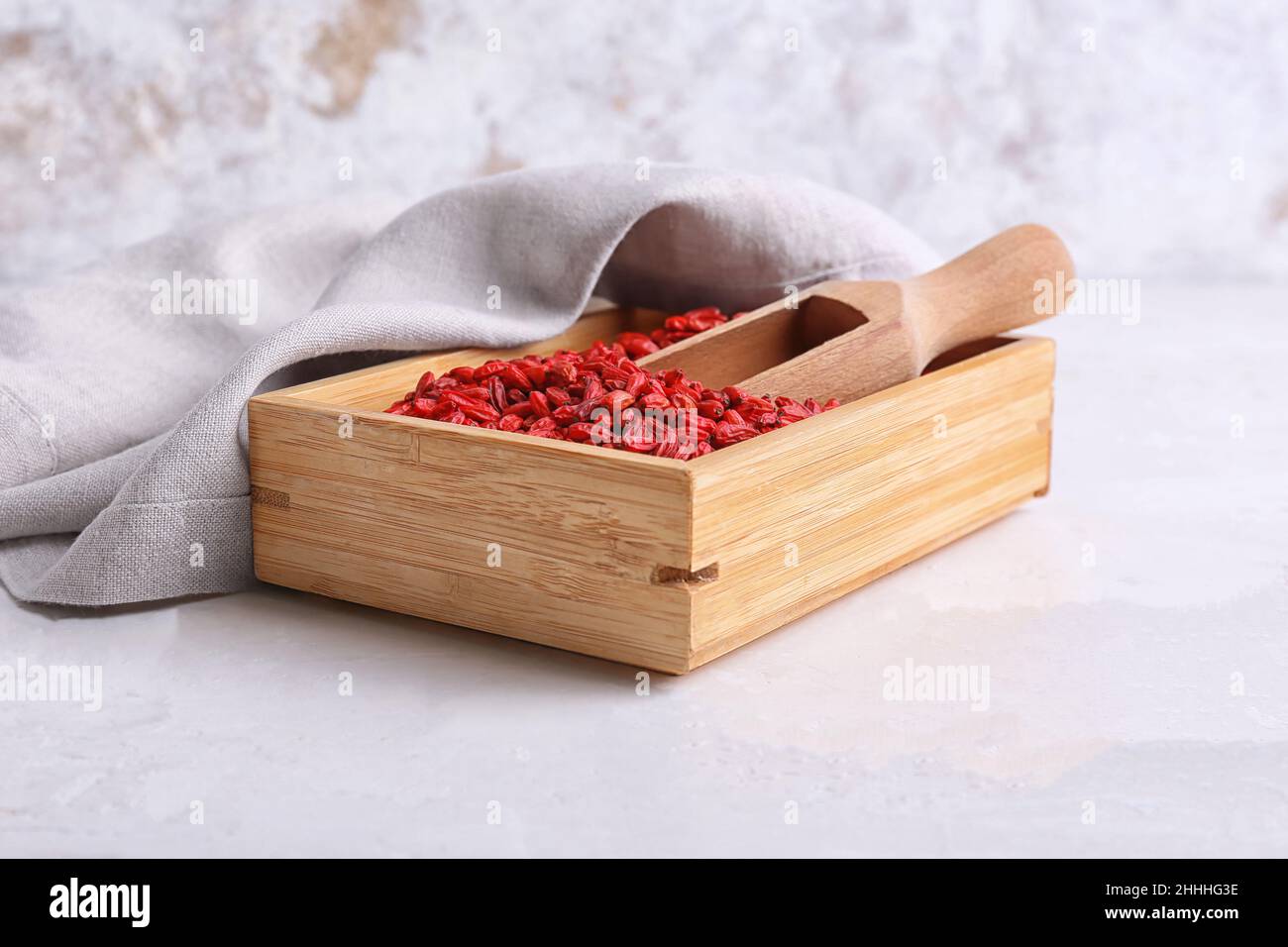 Scatola e paletta con frutti di bosco secchi su sfondo chiaro Foto Stock