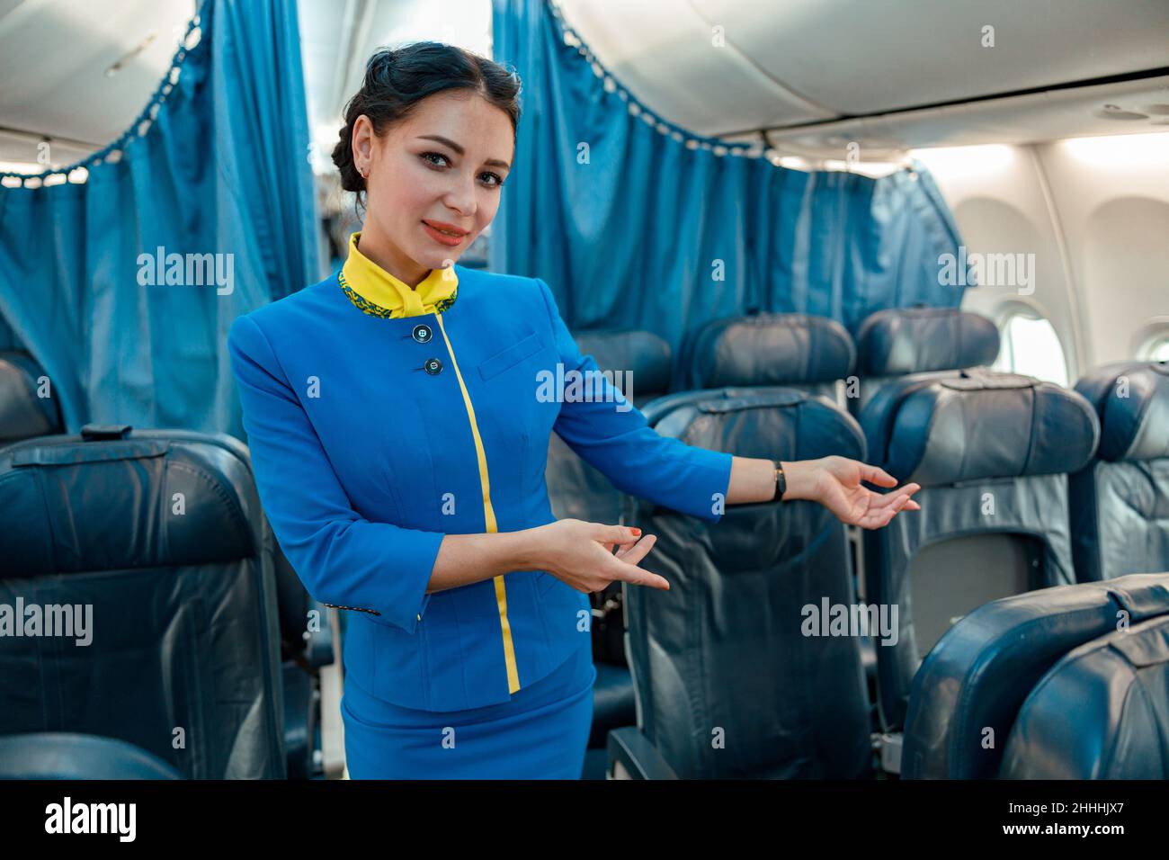Donna stewardess suggerendo di prendere il posto del passeggero in aereo Foto Stock