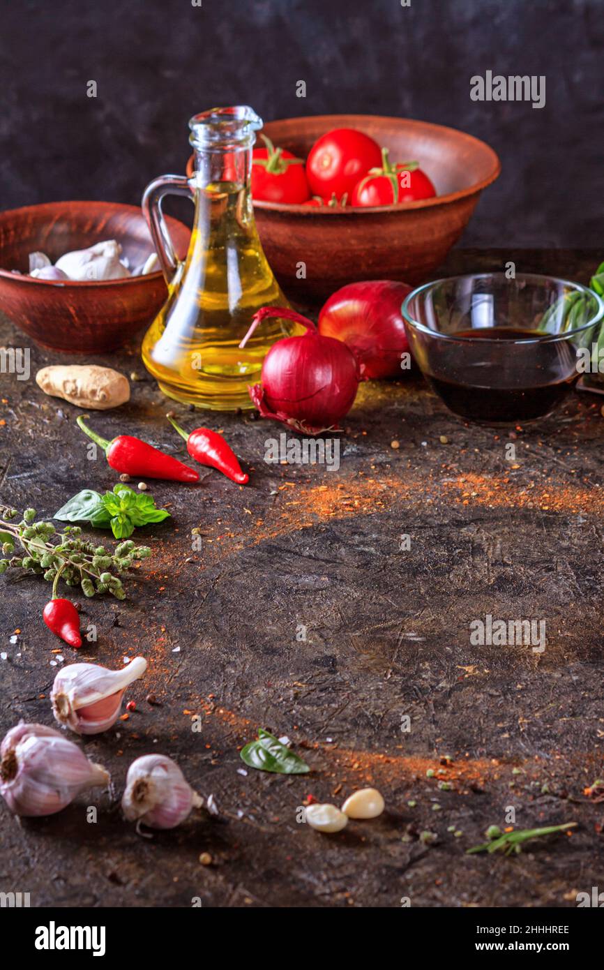 Sfondo culinario con superficie in pietra da cucina, olio d'oliva in una brocca e verdure. Spazio vuoto per menu o ricetta con messa a fuoco selettiva Foto Stock
