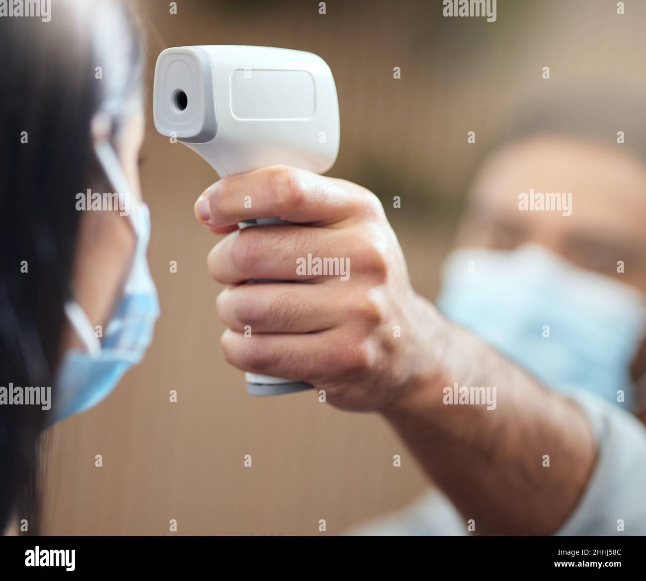 Tempo di temperatura. Scatto corto di una donna d'affari irriconoscibile che indossa una maschera e che ha la sua temperatura presa mentre sta alla testa di un Foto Stock