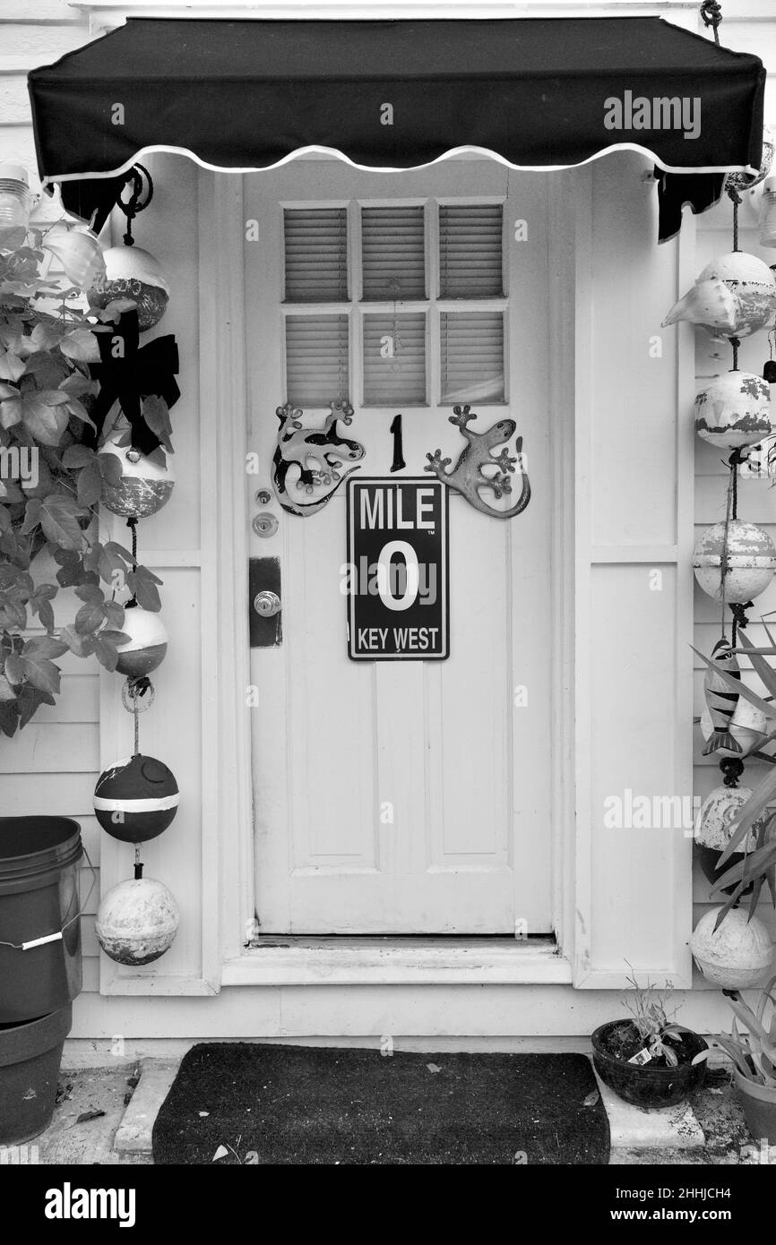 Porta anteriore con Mile Marker "0" e geckos decorativi a Key West, Florida, Florida, Stati Uniti. Le boe da pesca pendenti e una tenda rossa circondano la porta. Tropi Foto Stock
