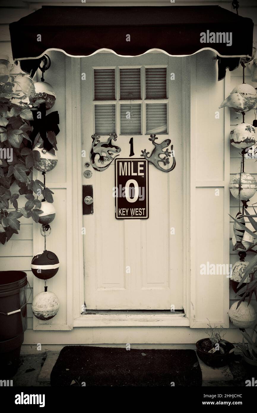 Porta anteriore con Mile Marker "0" e geckos decorativi a Key West, Florida, Florida, Stati Uniti. Le boe da pesca pendenti e una tenda rossa circondano la porta. Tropi Foto Stock