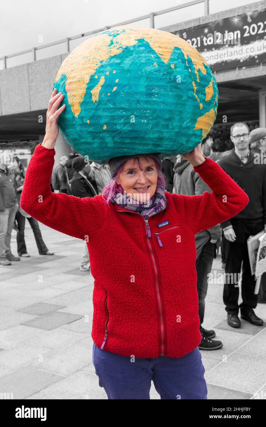 Donna che tiene il pianeta del mondo sulla sua testa a dimostrazione e marzo per la Giornata Globale d'azione, Bournemouth, Dorset UK nel mese di novembre Foto Stock