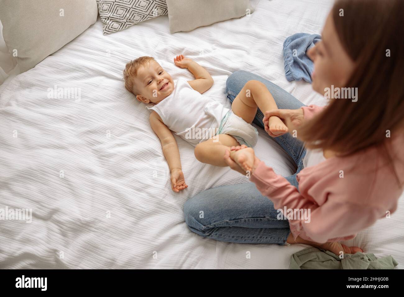 Giovane signora con il suo bambino durante il cambio dei vestiti Foto Stock