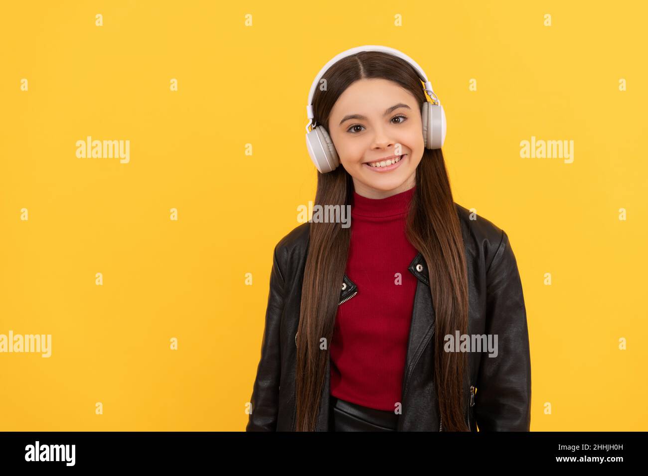 ragazza felice ascoltare musica in cuffie su sfondo giallo con spazio copia, musica Foto Stock