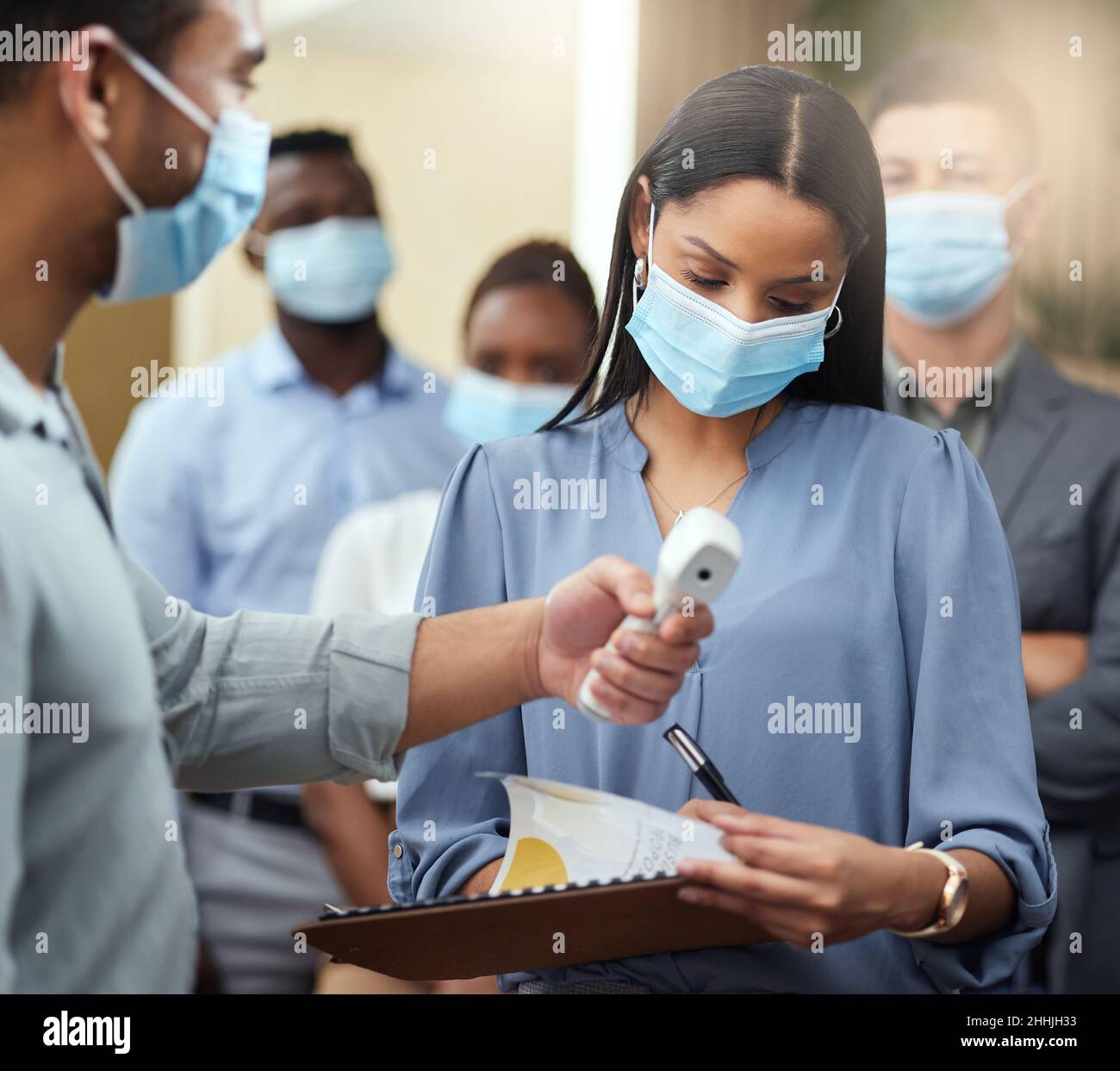 Via. Scatto corto di una giovane donna d'affari attraente che indossa una maschera e che passa attraverso lo schermo covid mentre sta alla testa di una coda dentro Foto Stock