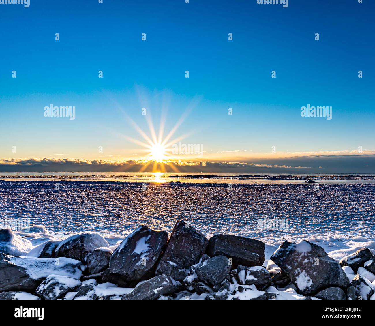 alba sopra la spiaggia ghiacciata vicino alle rocce Foto Stock