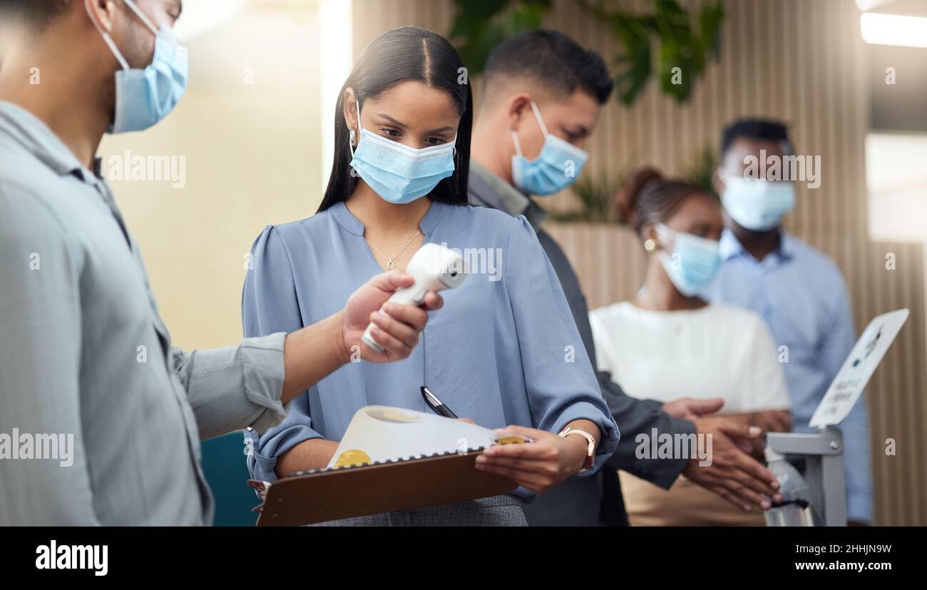 Soddisfare tutti i requisiti di screening. Scatto corto di una giovane donna d'affari attraente che indossa una maschera e che passa attraverso schermo covid mentre in piedi Foto Stock