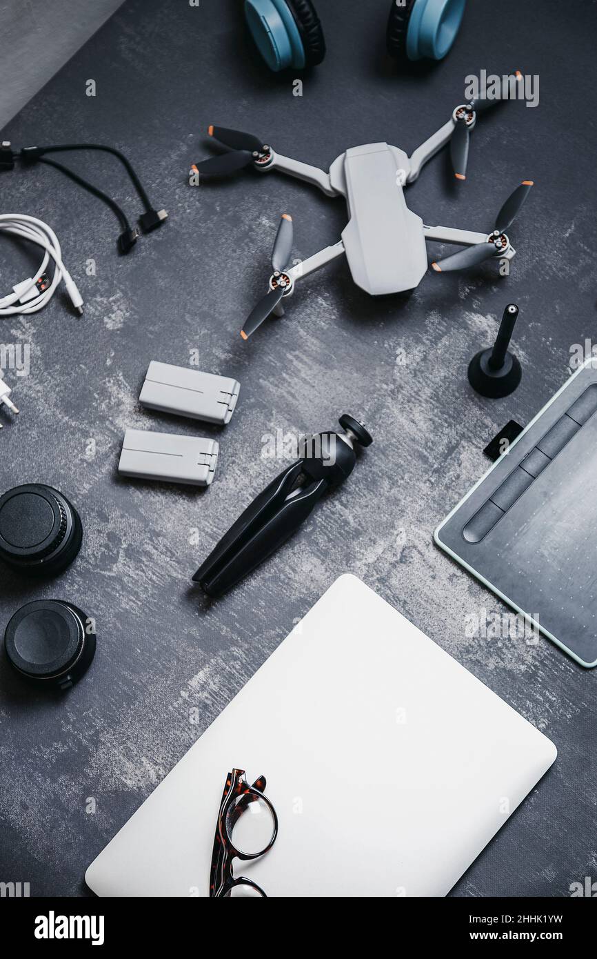 Vista dall'alto dei moderni apparecchi per drone UAV, inclusi caricabatterie e cavalletto vicino a netbook e tablet grafico su una scrivania grigia Foto Stock