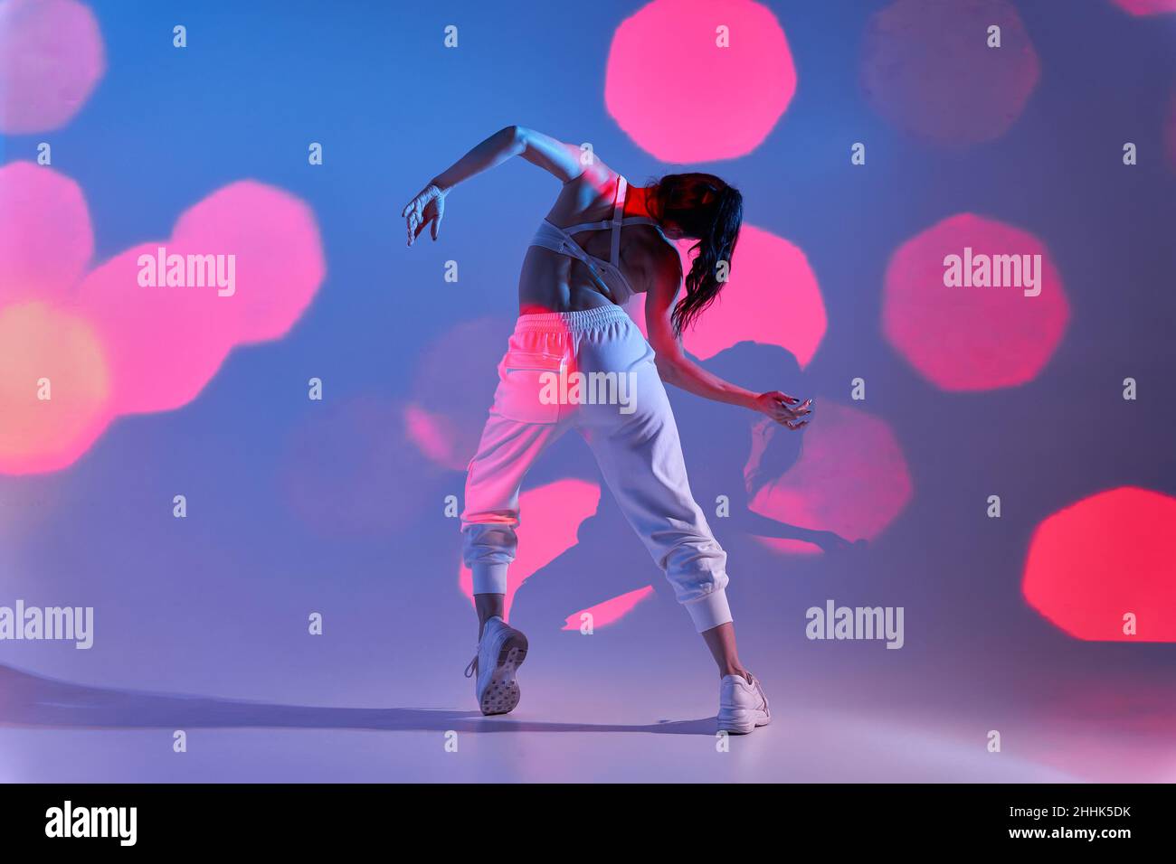 Vista posteriore del corpo di danze femminili irriconoscibili sullo studio delle timpe con illuminazione bokeh Foto Stock