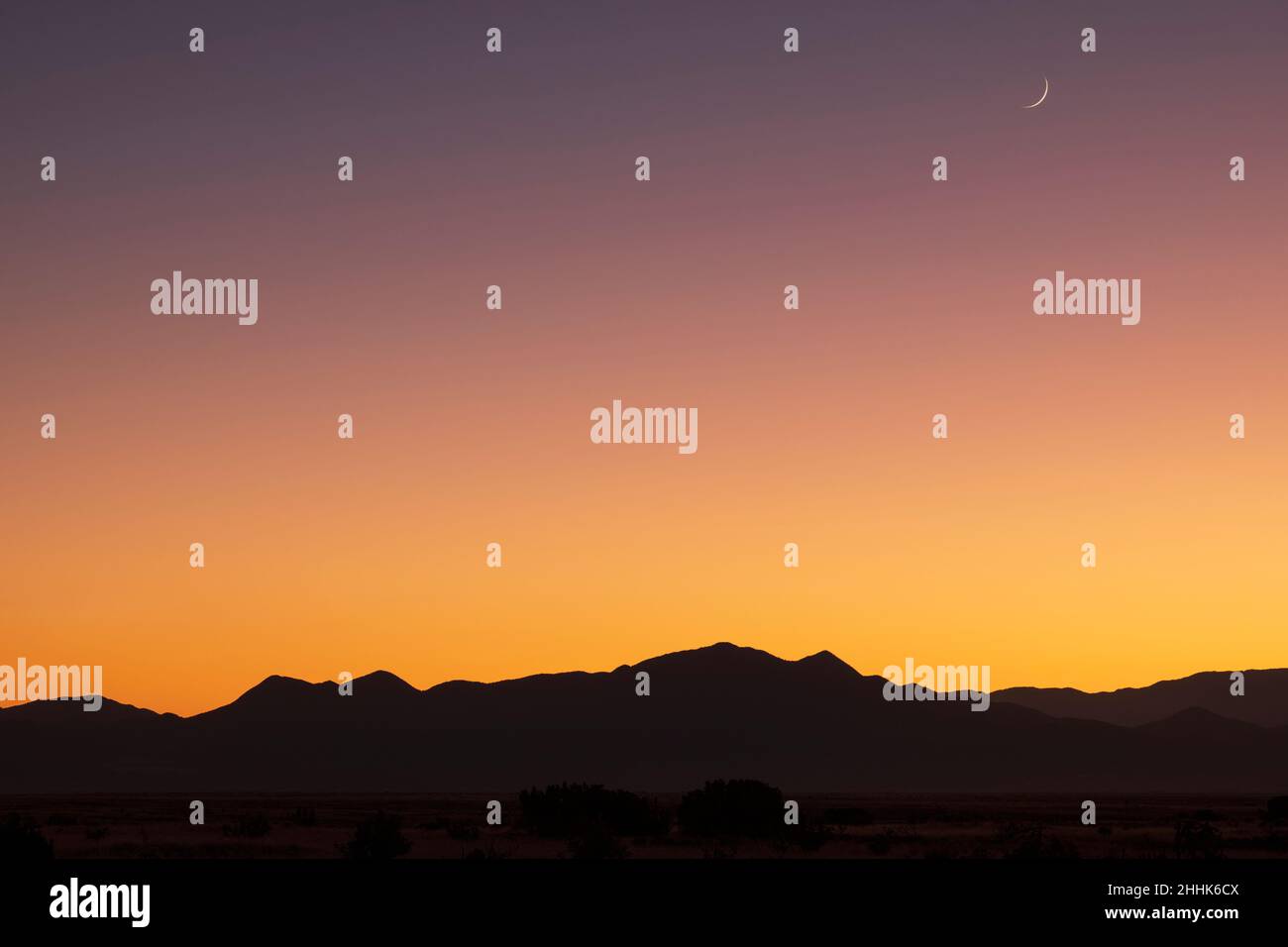 USA, New Mexico, Santa Fe, Crescent moon sopra le montagne di Jemez al tramonto Foto Stock