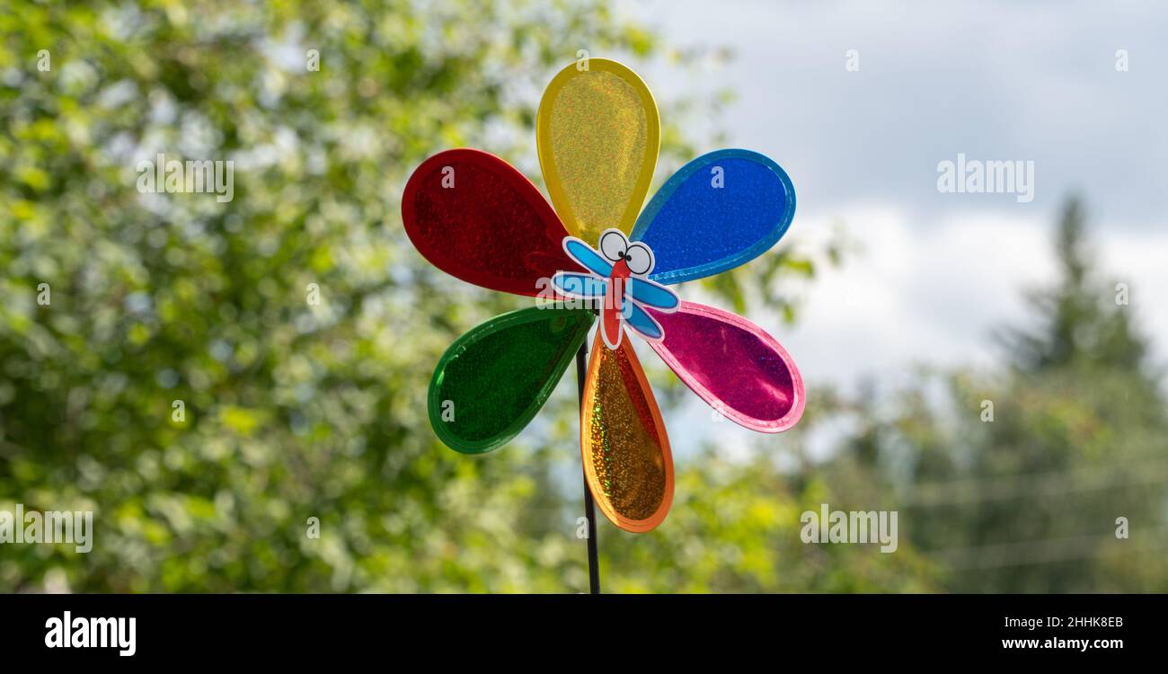 Movimento di rotazione del mulino a vento. Paletta meteo colorata su sfondo naturale. Paletta d'aria in movimento Foto Stock