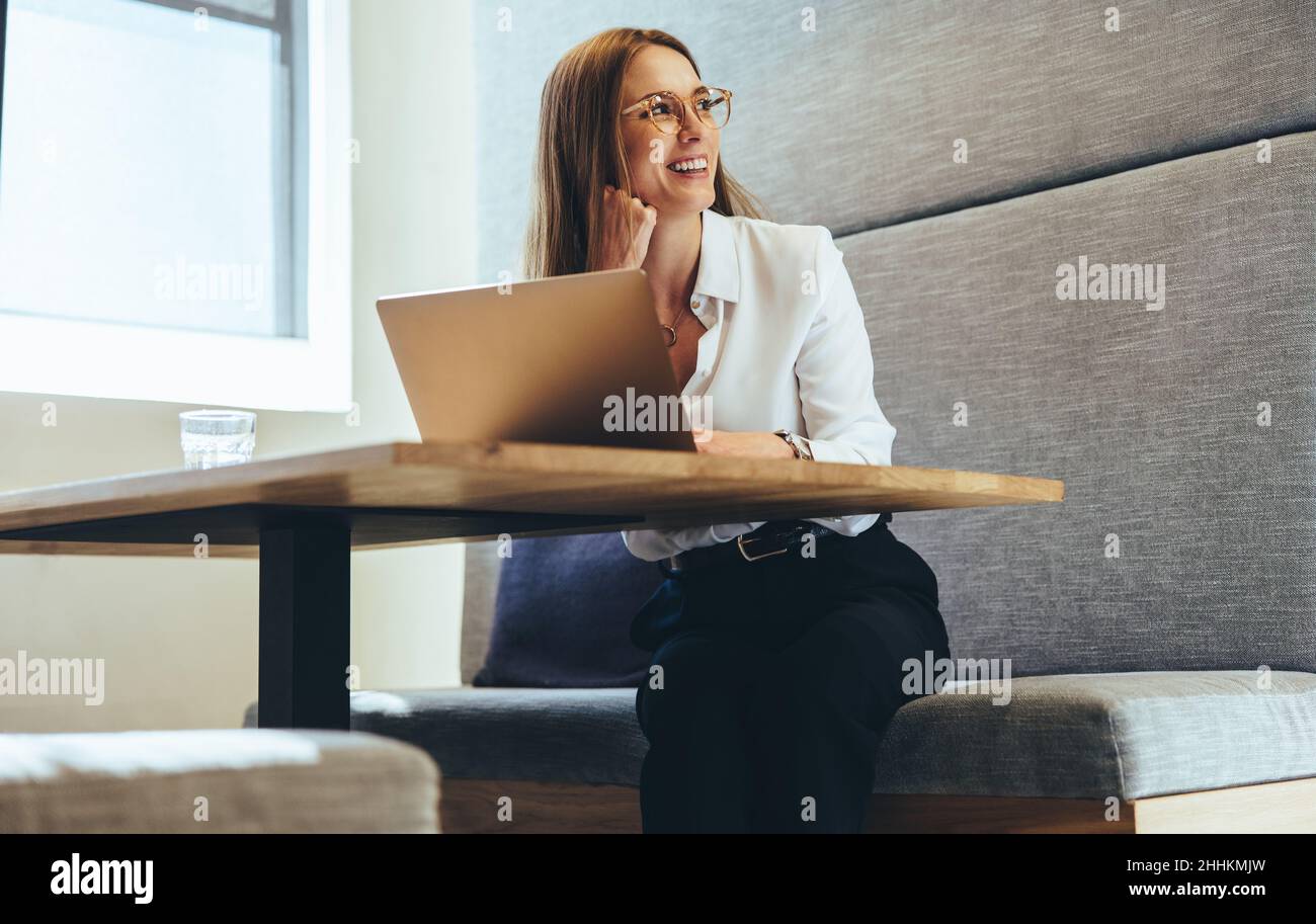 Donna d'affari eccitata che guarda via pensieroso. Felice giovane donna d'affari sorridente mentre contempla le idee di affari. Giovane imprenditore femminile worki Foto Stock