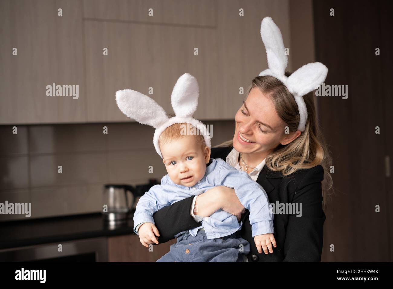 Madre e bambino alla vigilia di Pasqua. Mamma e bambino con orecchie di  coniglio insieme in cucina. Genitore e bambino giocano in casa in  primavera. Casa accogliente e primavera Foto stock -