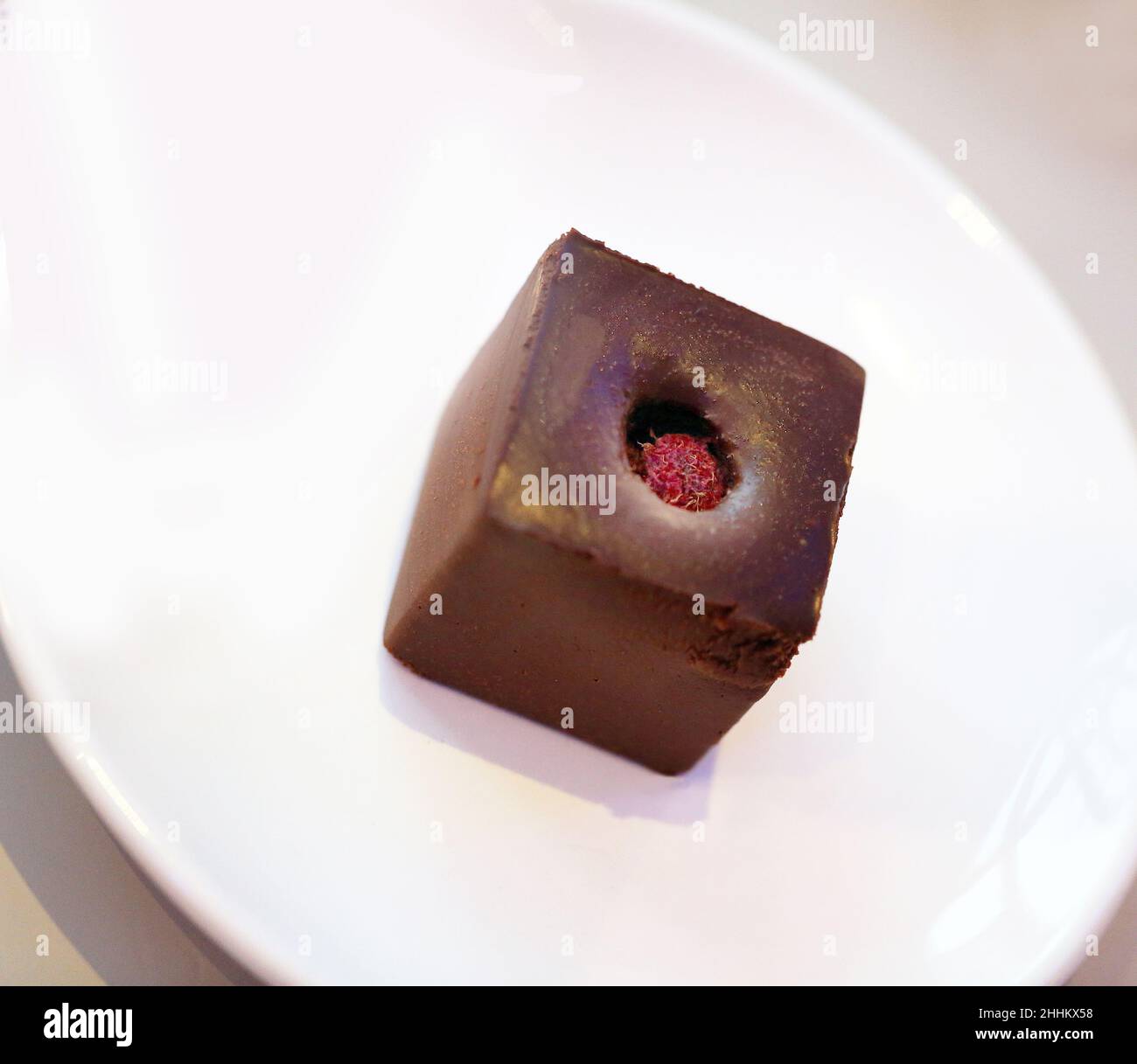 Foto di un cubo di cioccolato con lamponi su sfondo bianco Foto Stock