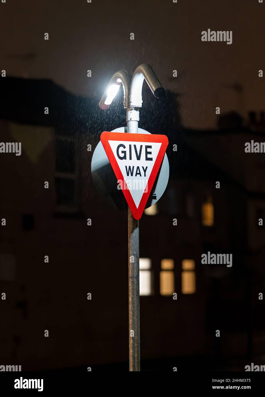 Dare modo strada segnaletica stradale luminoso di notte al buio. Le luci a LED illuminano la segnaletica triangolare segnalando il traffico di incrocio di busto nell'oscurità. Foto Stock