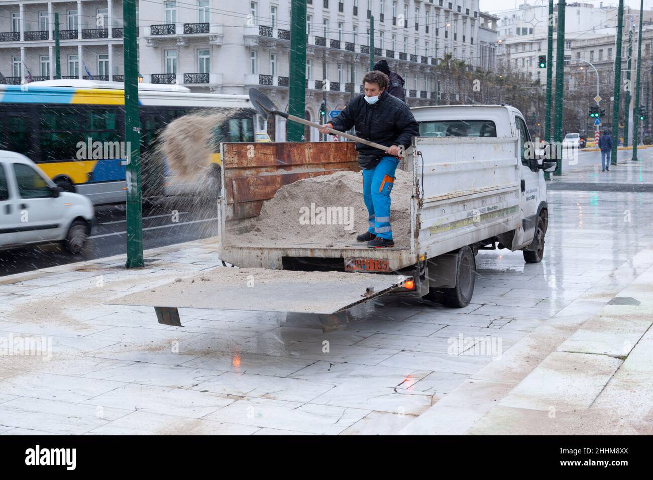 Dipendente del servizio tecnico del comune di Atene gettando sale anti-ghiaccio per prevenire la formazione di ghiaccio durante la nevicata ad Atene Foto Stock
