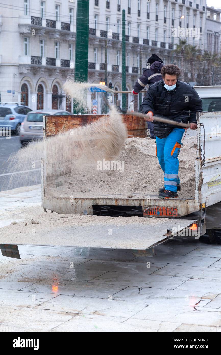 Dipendente del servizio tecnico del comune di Atene gettando sale anti-ghiaccio per prevenire la formazione di ghiaccio durante la nevicata ad Atene Foto Stock