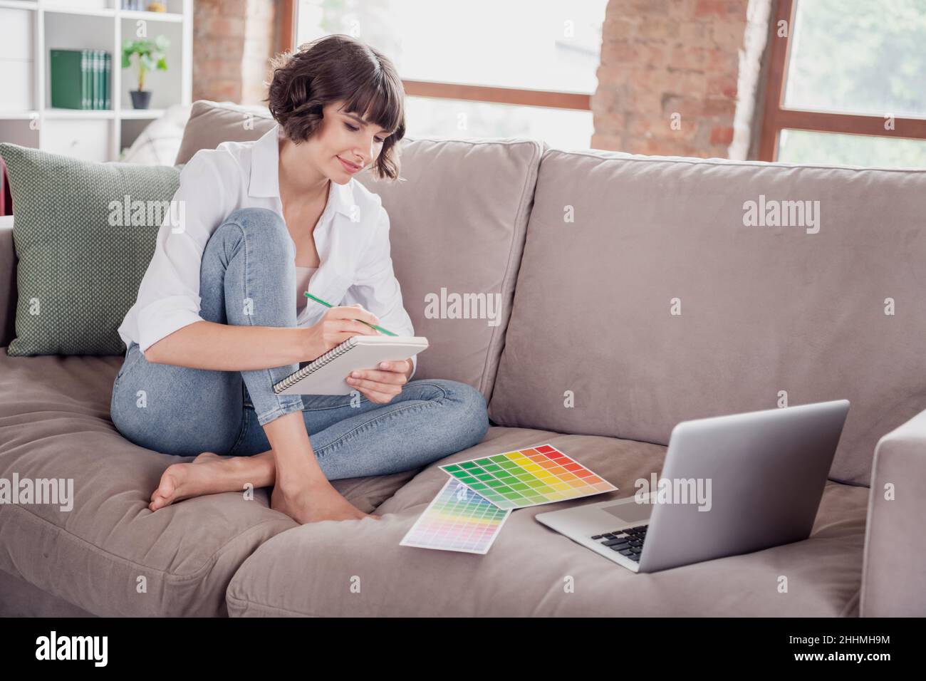 Foto grafica femminile disegno in blocknote vicino a laptop colori palette Foto Stock