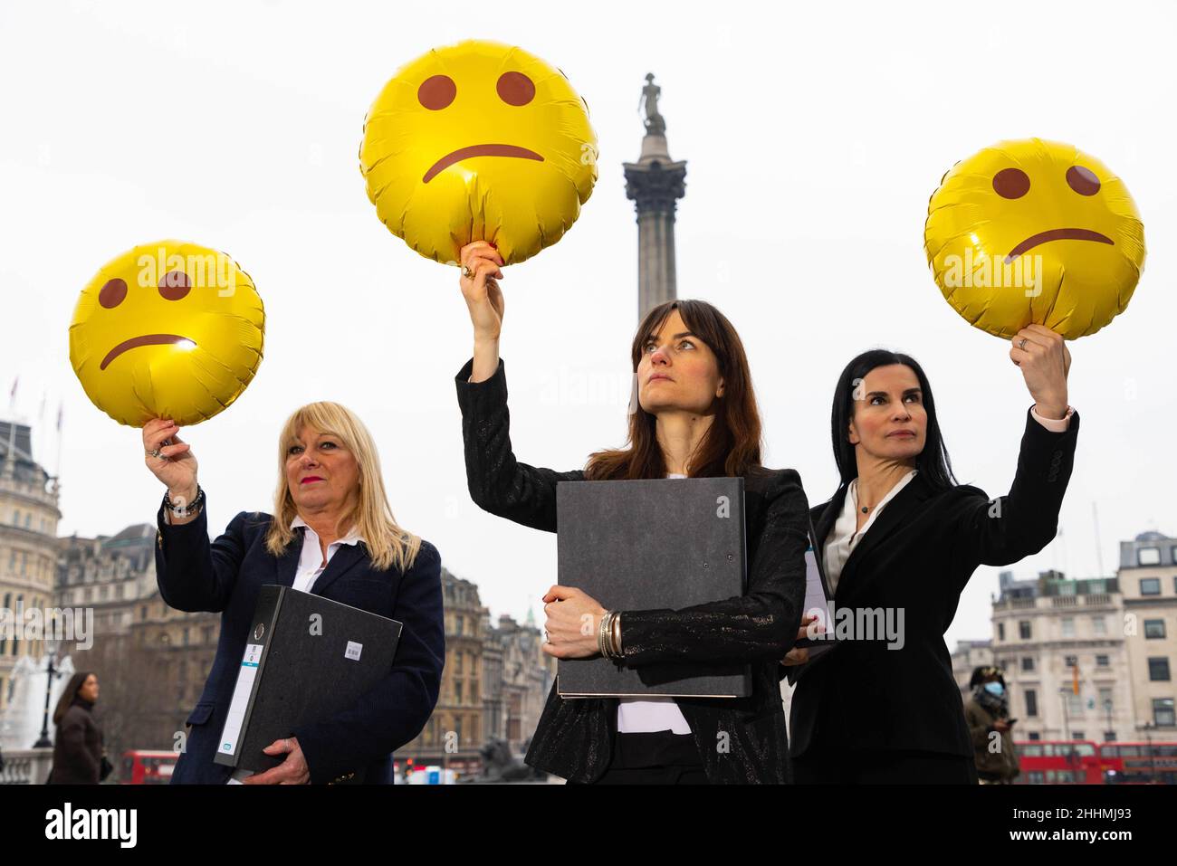 EDITORIALE USO SOLO i lavoratori che rappresentano l'industria 'reale estate', che è stato valutato il settore più sfelice, tenere emoji-a forma di palloncini per illustrare i risultati di effettivamente 'Work Happiness Score', il più grande studio del mondo di felicità del lavoro, Trafalgar Square, Londra. Data foto: Martedì 25 gennaio 2022. Foto Stock