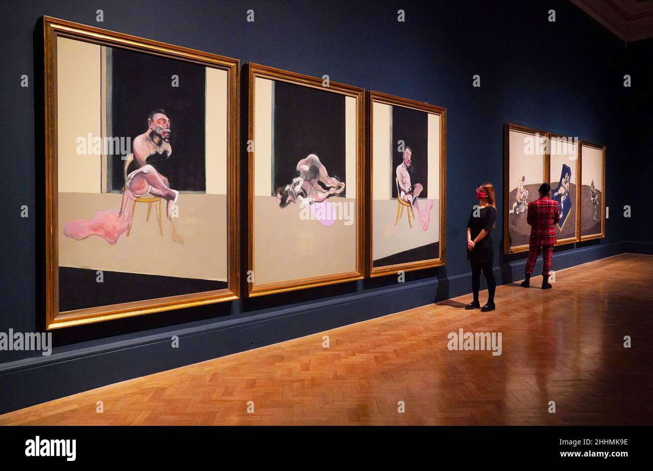 I membri dello staff guardano due trittici di Francis Bacon, 'Triptych August 1972' (a sinistra) e 'Three Figures in a Room' (a destra) esposti nella mostra Francis Bacon: Uomo e bestia alla Royal Academy of Arts di Londra che si svolge dal 29 gennaio al 17 aprile. Data foto: Martedì 25 gennaio 2022. Foto Stock