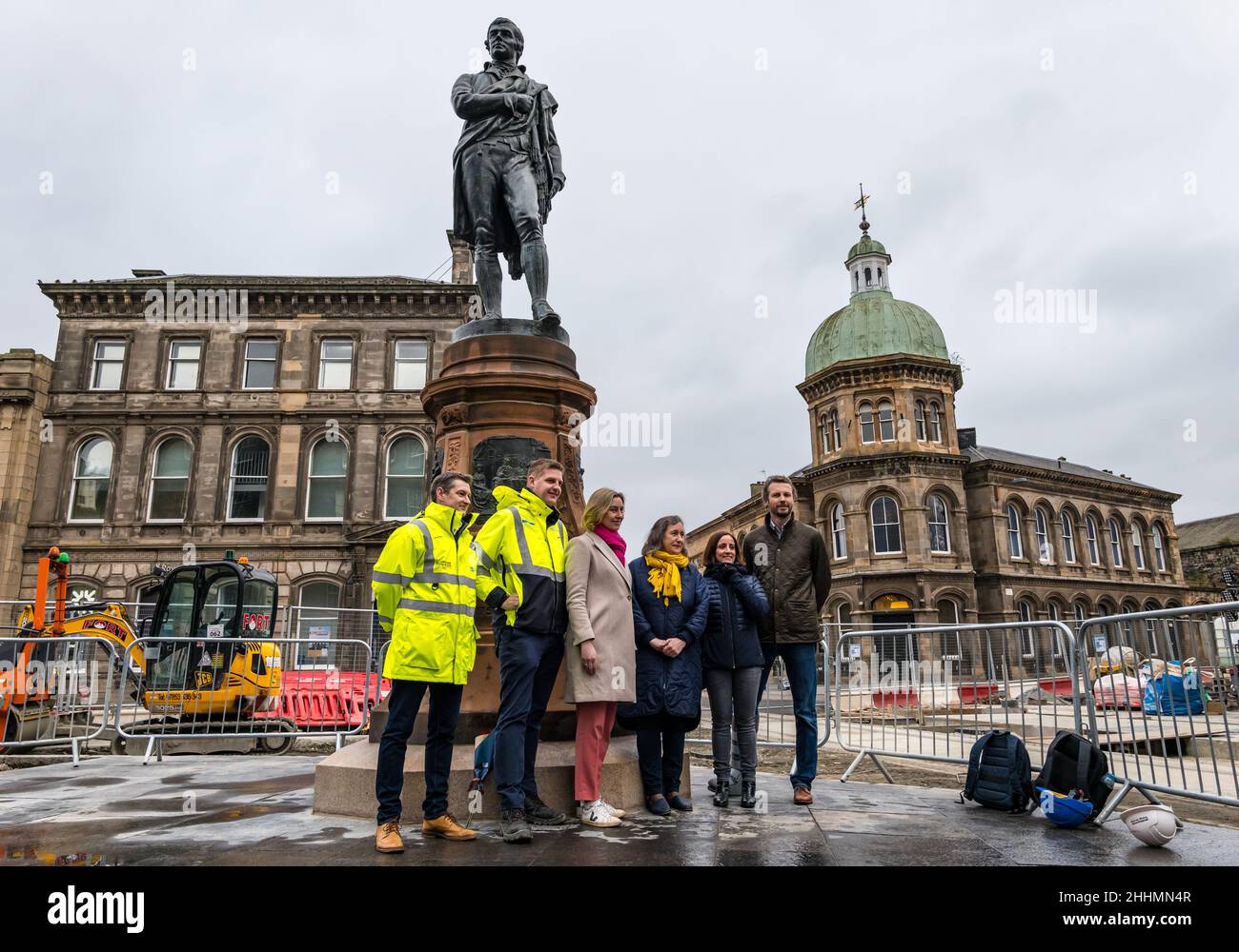 Leith, Edimburgo, Scozia, Regno Unito, 25 gennaio 2022. La statua di Robert Burns svelata: La statua, che è stata rimossa nel 2019 per i tram per i lavori di costruzione di Newhaven, ritorna a Bernard Street recentemente restaurato sulla notte Burns. La statua fu eretta dal Leith Burns Club nel 1898. Su ciascun lato del piedistallo si trova un pannello basato su una delle poesie del Bard. Nella foto: Il Consigliere Lesley Macinnes si unisce ai membri del progetto di costruzione alla presentazione Foto Stock