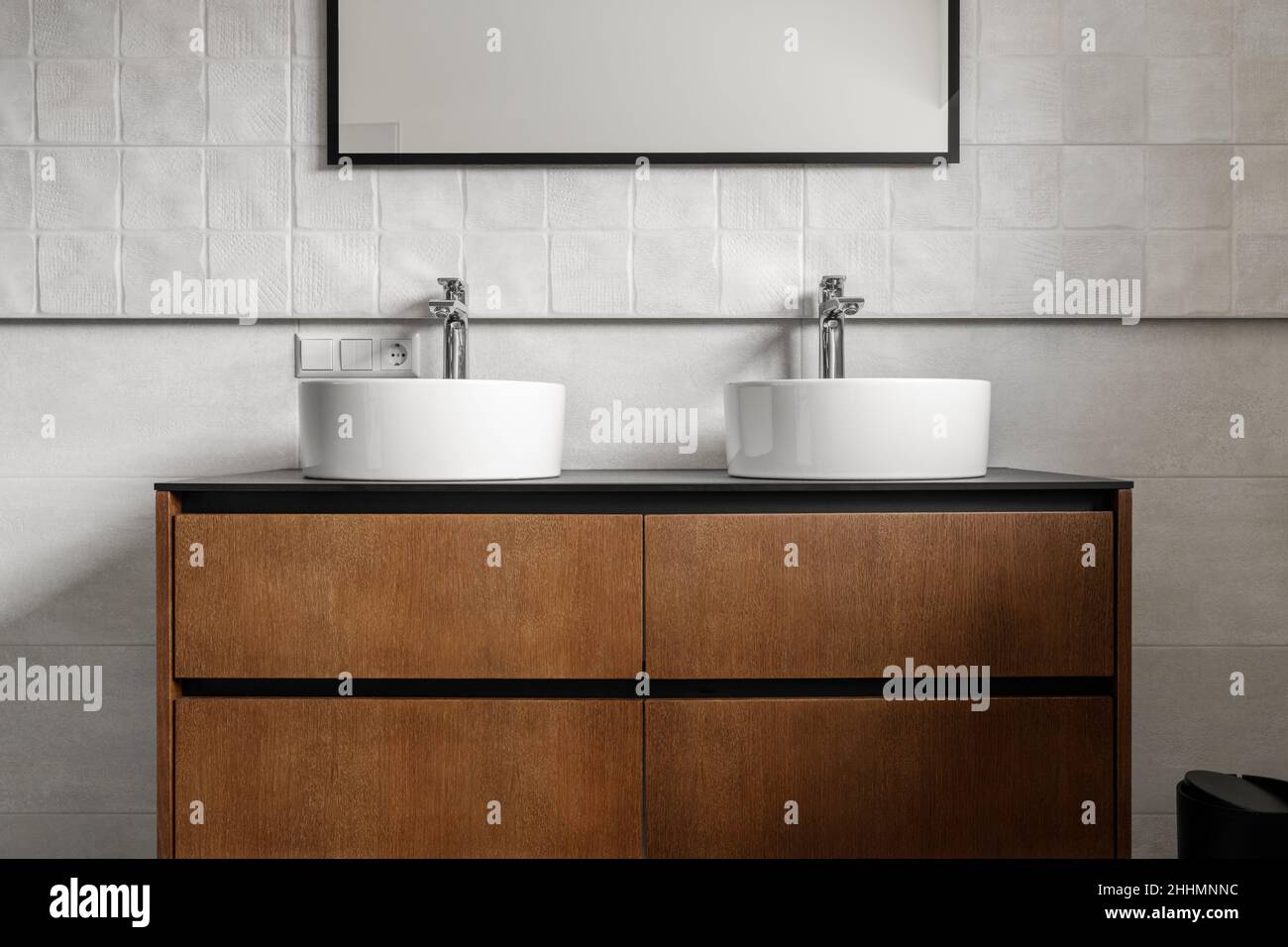 Bagno moderno vanity unita' con due lavandini rotondi in ceramica, rubinetti cromati e specchio con cornice nera, racconti bianchi e armadietto in legno. Bar contemporaneo Foto Stock