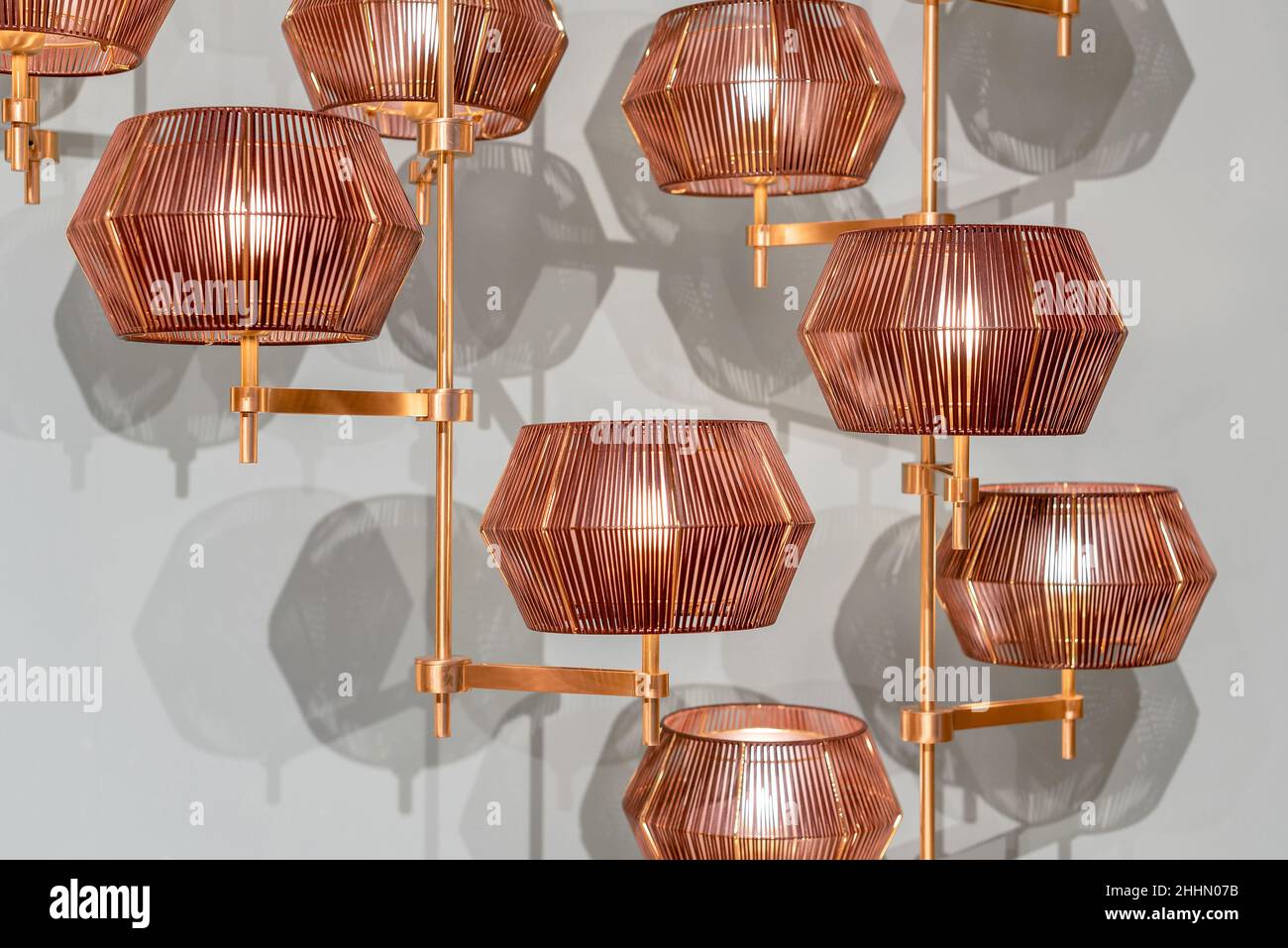 Lampadario moderno e creativo con paralume di forma geometrica e dettagli in rame appesi contro pareti bianche Foto Stock