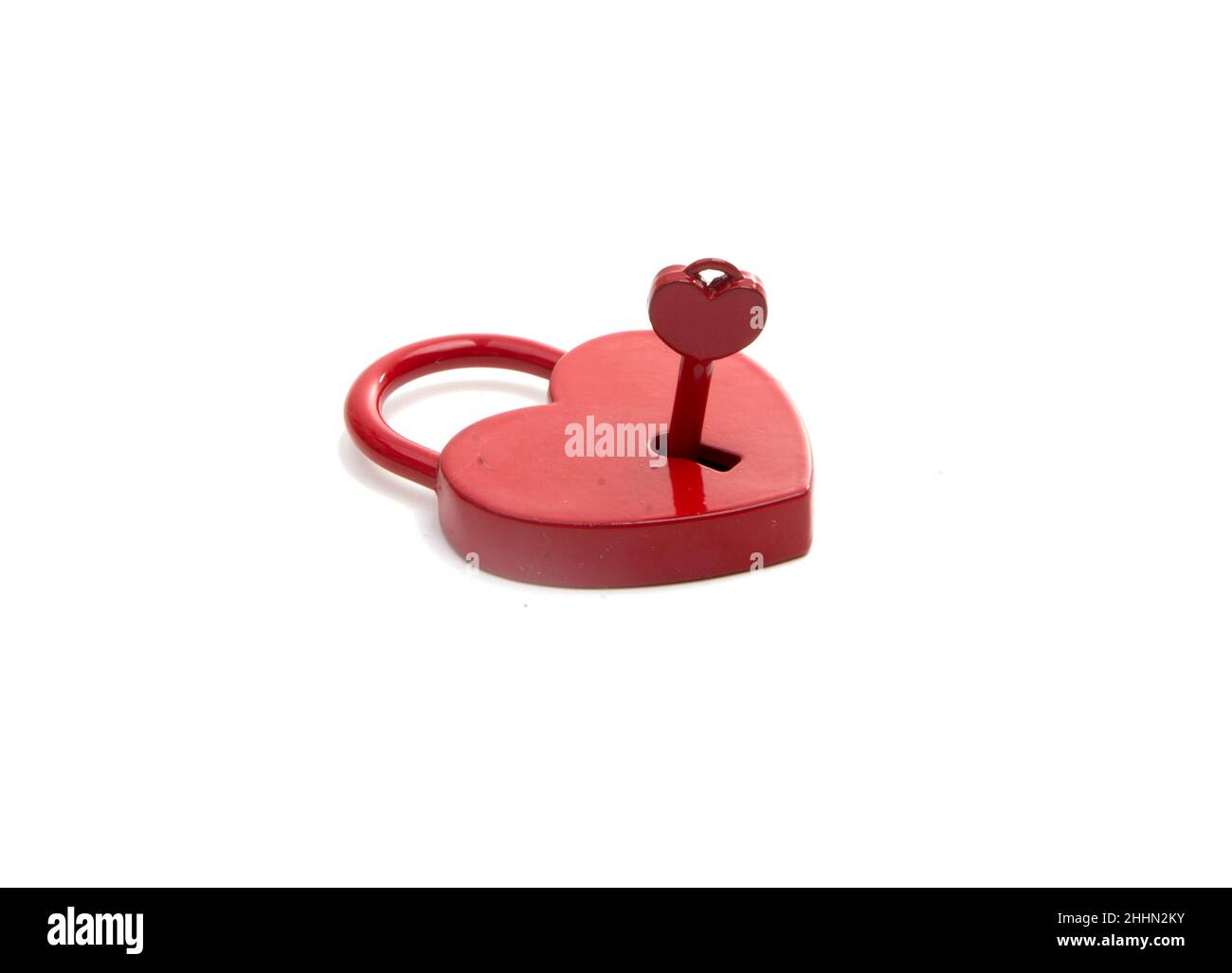 cuore rosso metalico con una chiave sul bianco Foto Stock