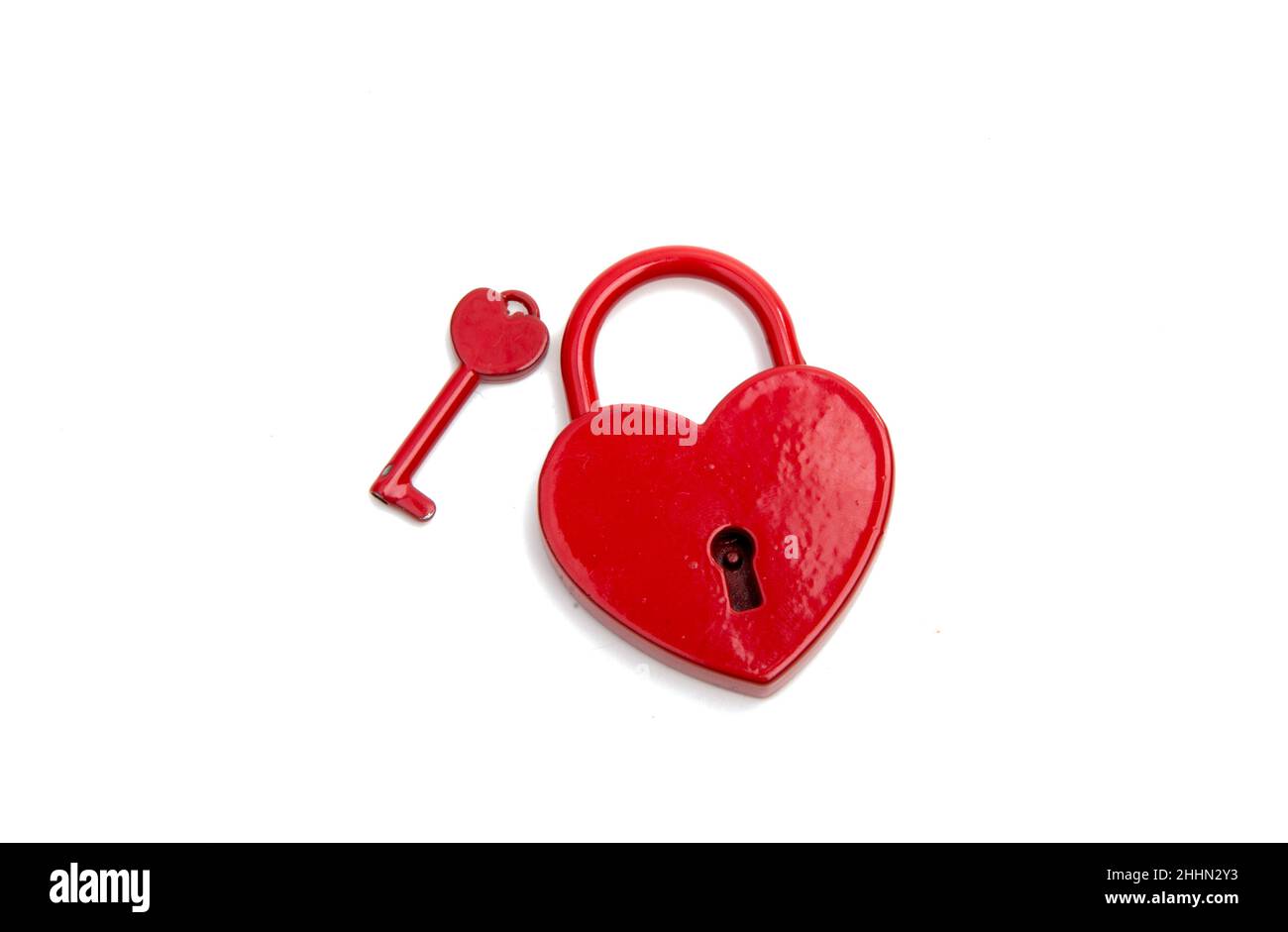 cuore rosso metalico con una chiave sul bianco Foto Stock