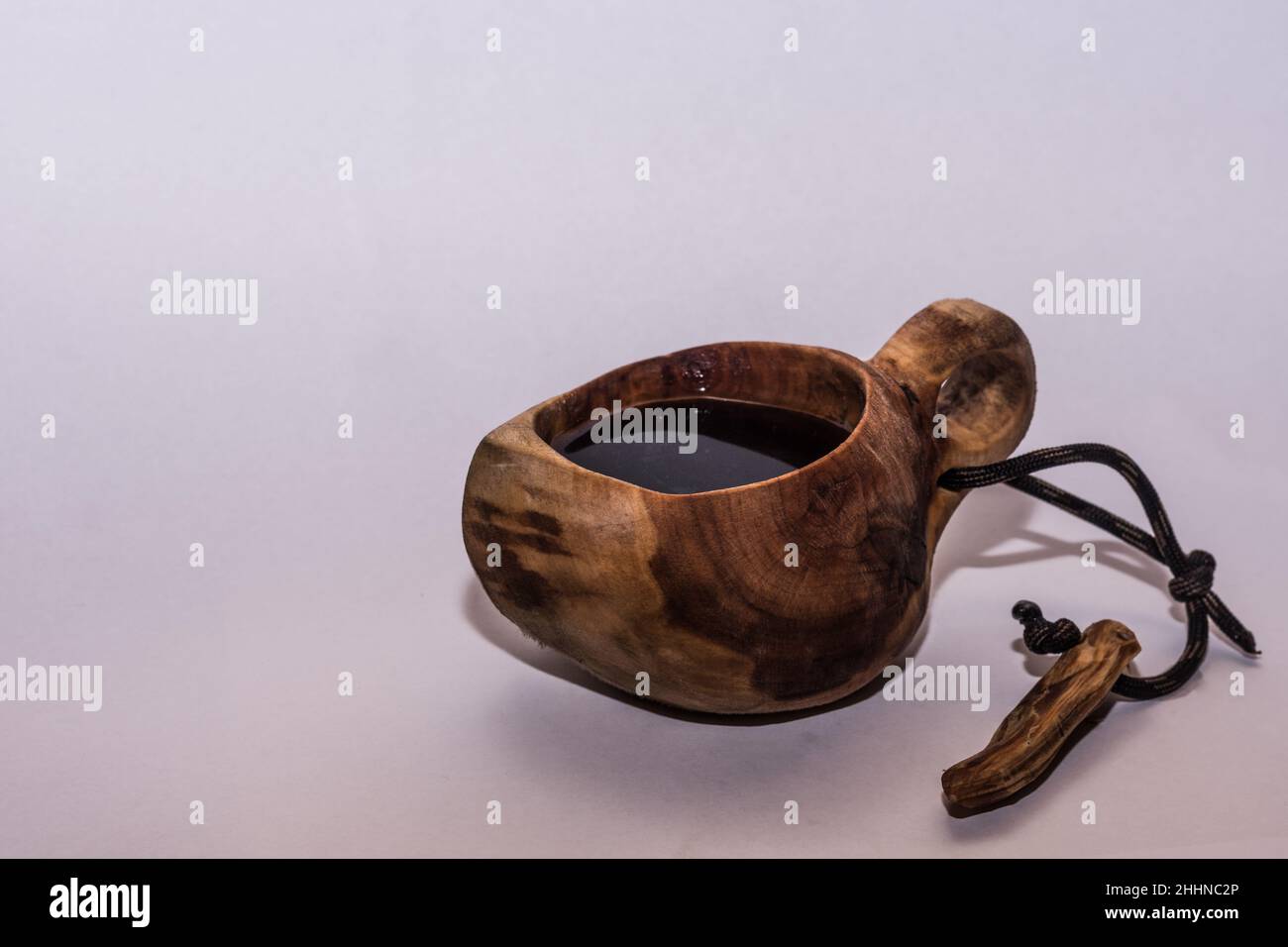 tazza di legno intagliata chiamata kuksa con un caffè per la boscaglia su sfondo grigio Foto Stock