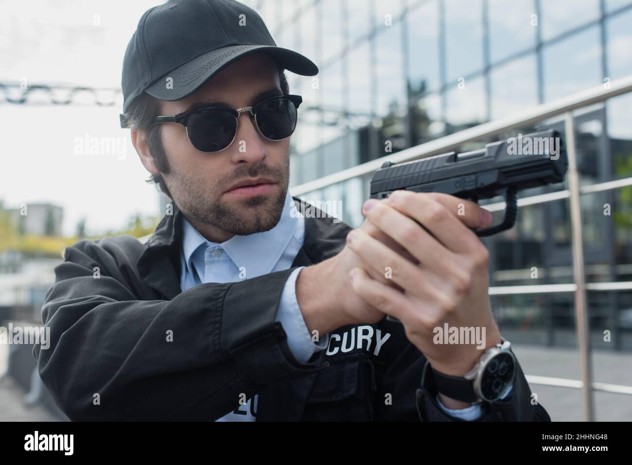 guardia giovane in uniforme e occhiali da sole che reggono la pistola all'aperto Foto Stock