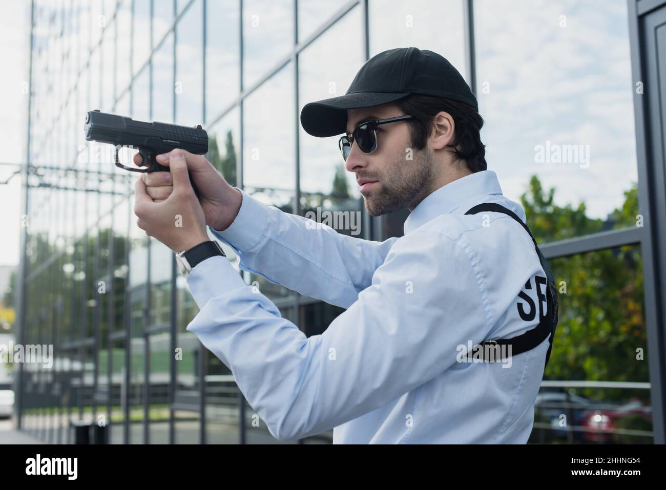 protezione giovane in cappuccio e occhiali da sole che reggono la pistola all'aperto Foto Stock