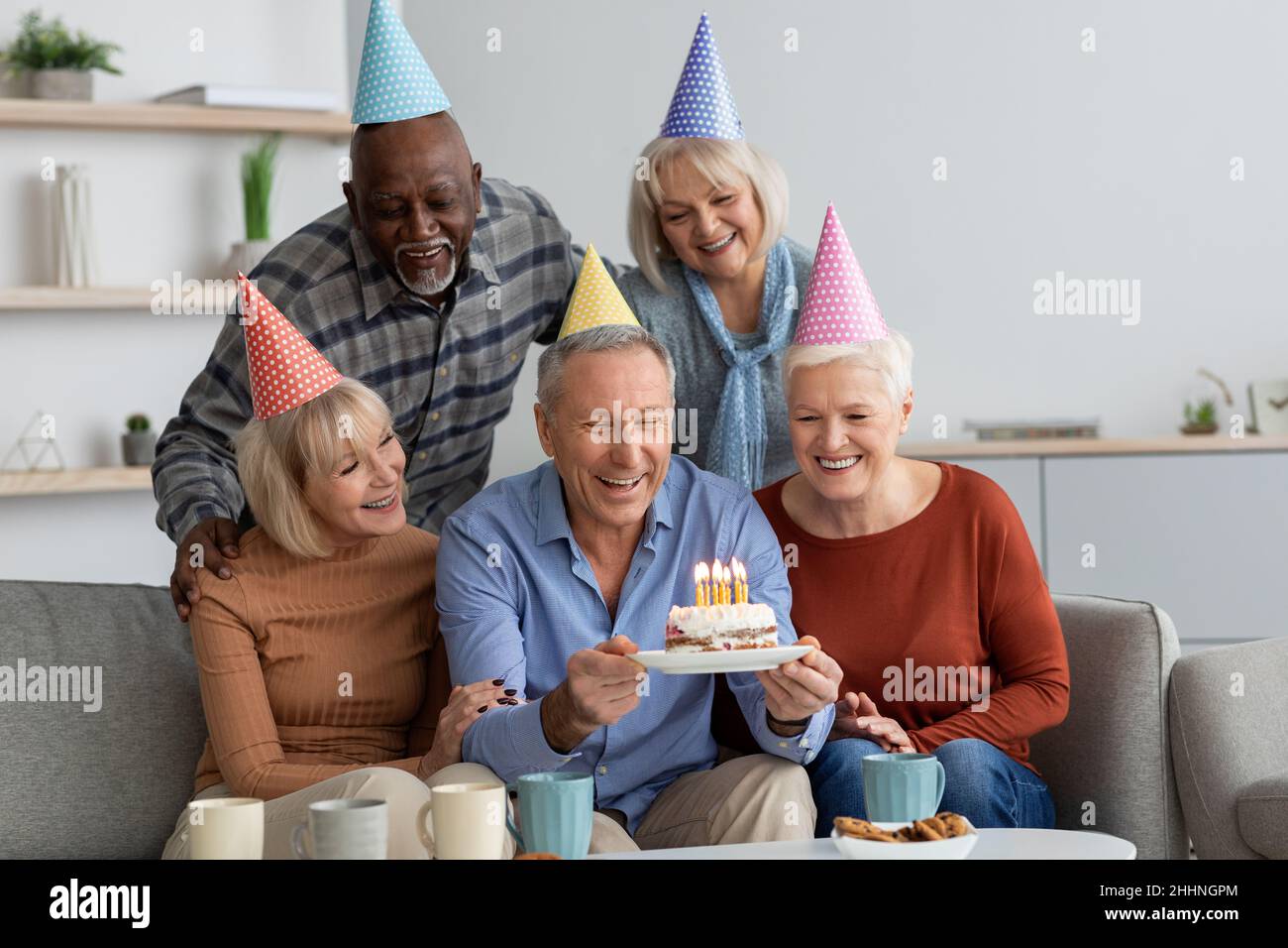 Gruppo multirazziale di persone anziane che hanno festa di compleanno a casa Foto Stock