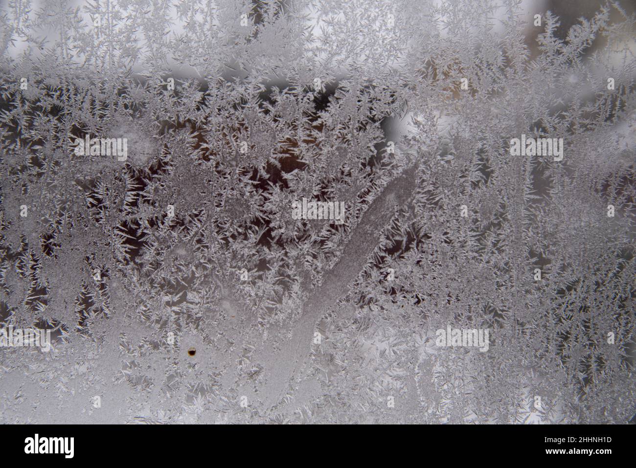 Motivo gelido su vetri sporchi della finestra in una giornata invernale nuvolosa. Foto Stock
