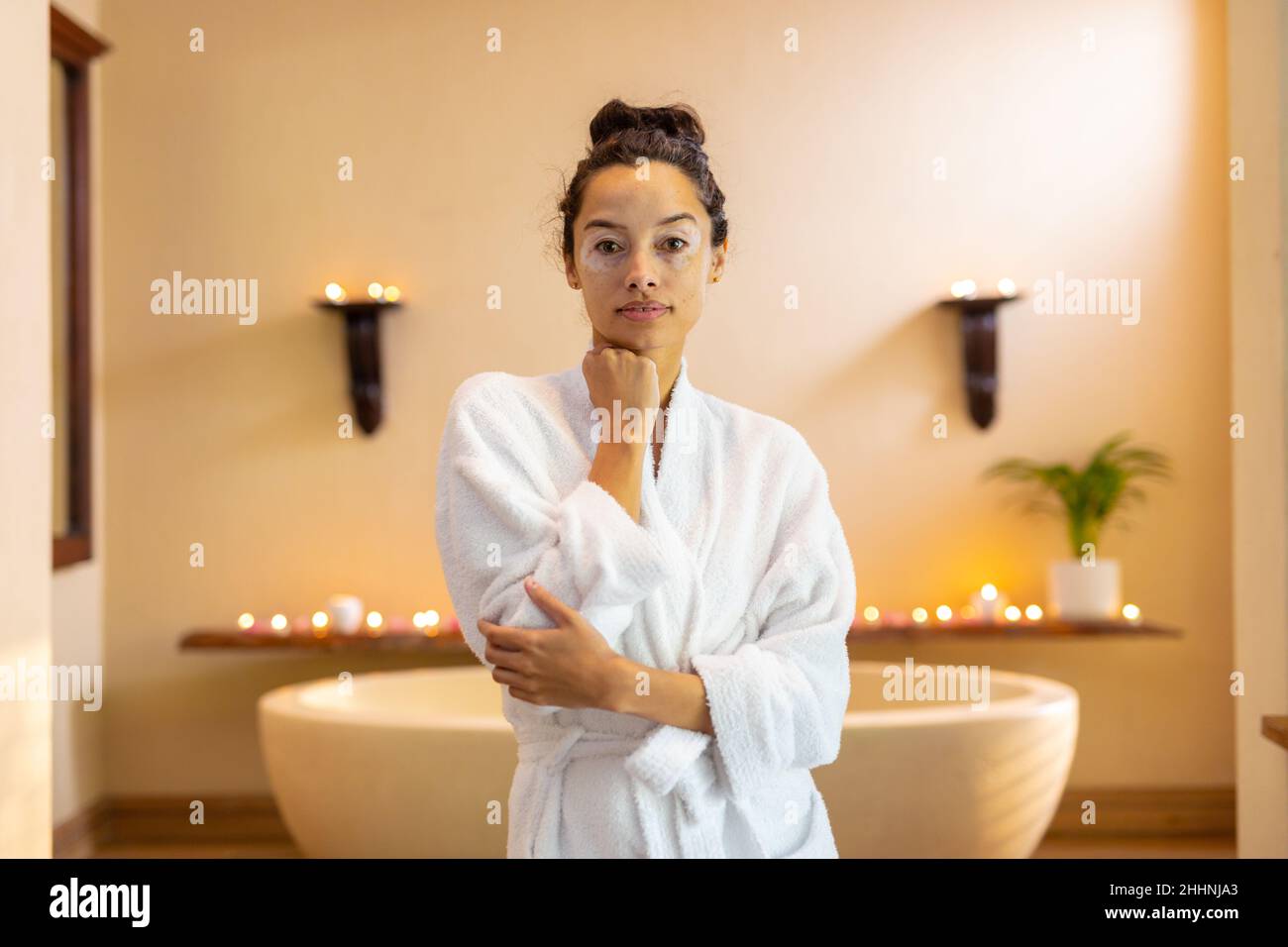 Ritratto di giovane donna biraciale con accappatoio in piedi davanti alla vasca idromassaggio. spa, cura del corpo, stile di vita, vitiligo e benessere. Foto Stock