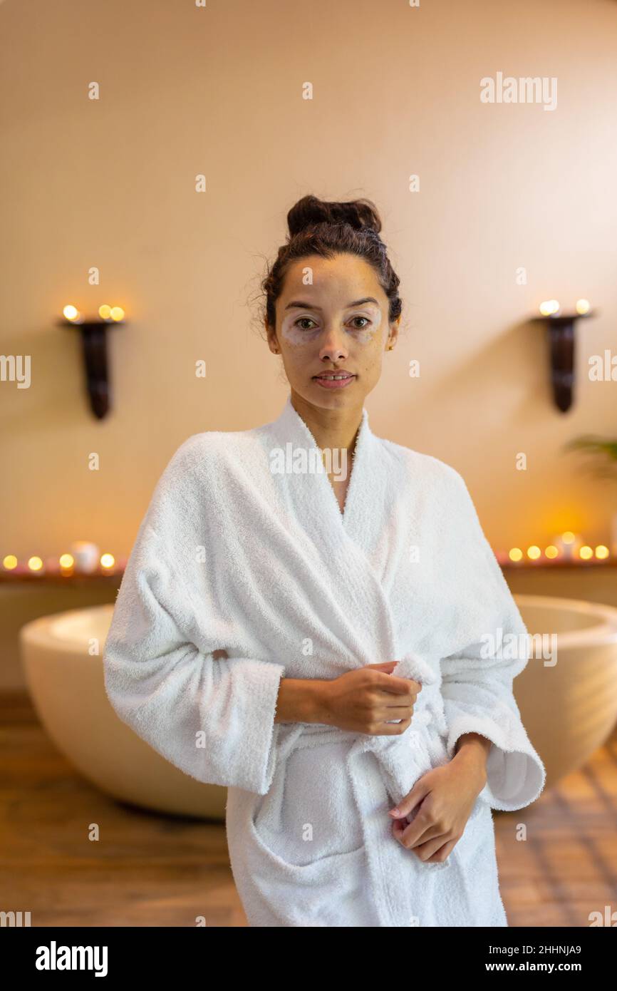 Ritratto di giovane donna fidata biraciale con accappatoio in piedi davanti alla vasca idromassaggio. spa, cura del corpo, stile di vita, vitiligo e benessere. Foto Stock