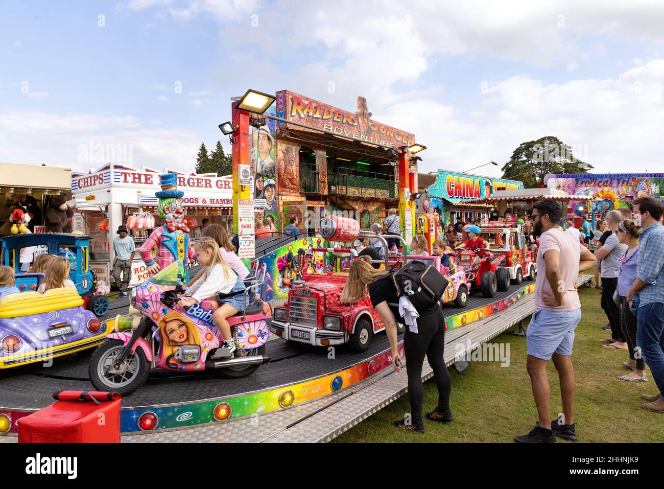 Fun Fair Regno Unito, genitori e bambini; bambini in un giro in fiera sotto il sole estivo, Harpenden Hertfordshire Regno Unito Foto Stock