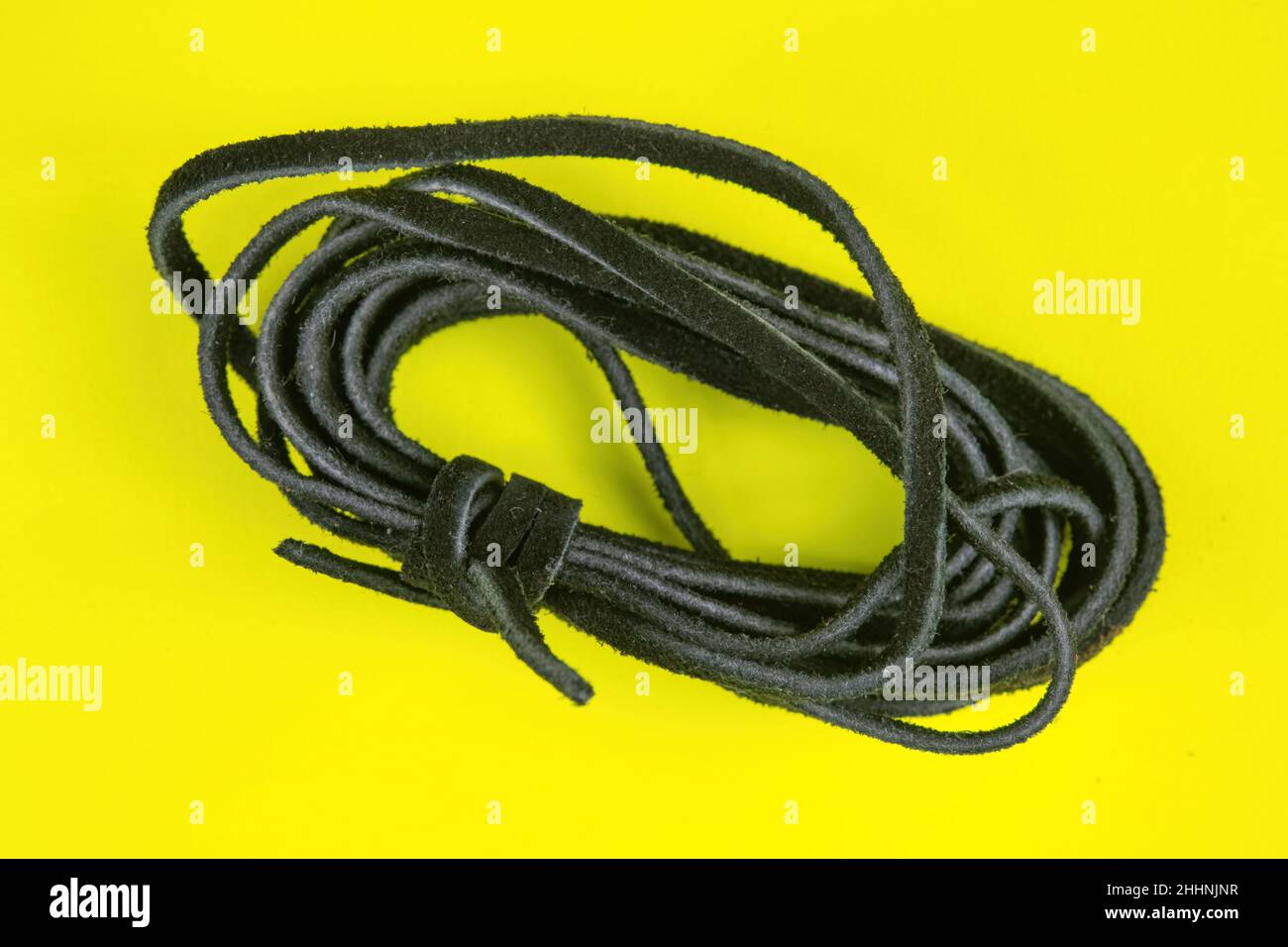 Un mazzo di corde nere scamosciate su sfondo giallo Foto Stock